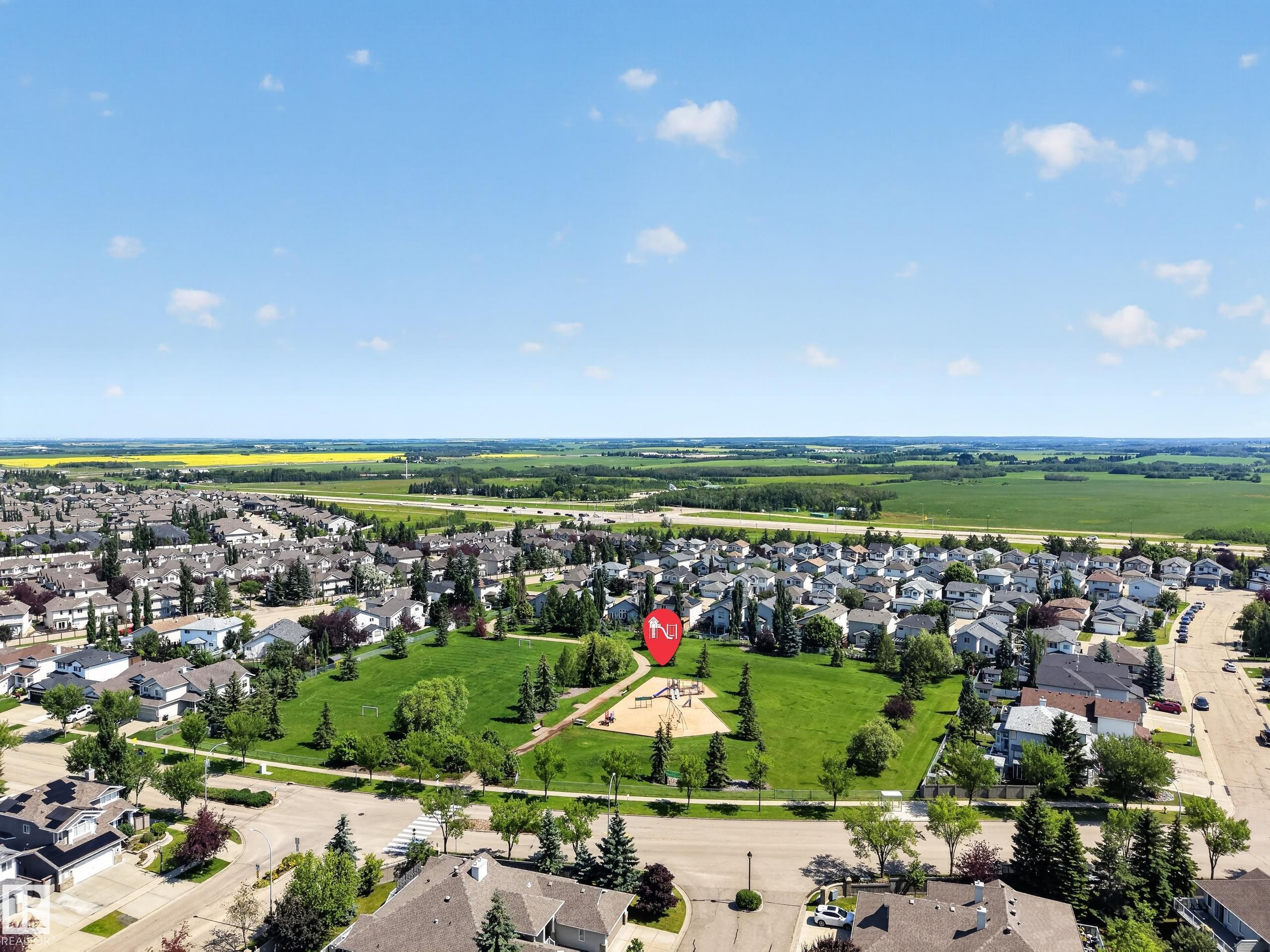 Aerial perspective showcasing a residential area with a prominent green space featuring a playground and mature trees - #7 155 Crocus Cr, Sherwood Park, AB - Outdoor With View