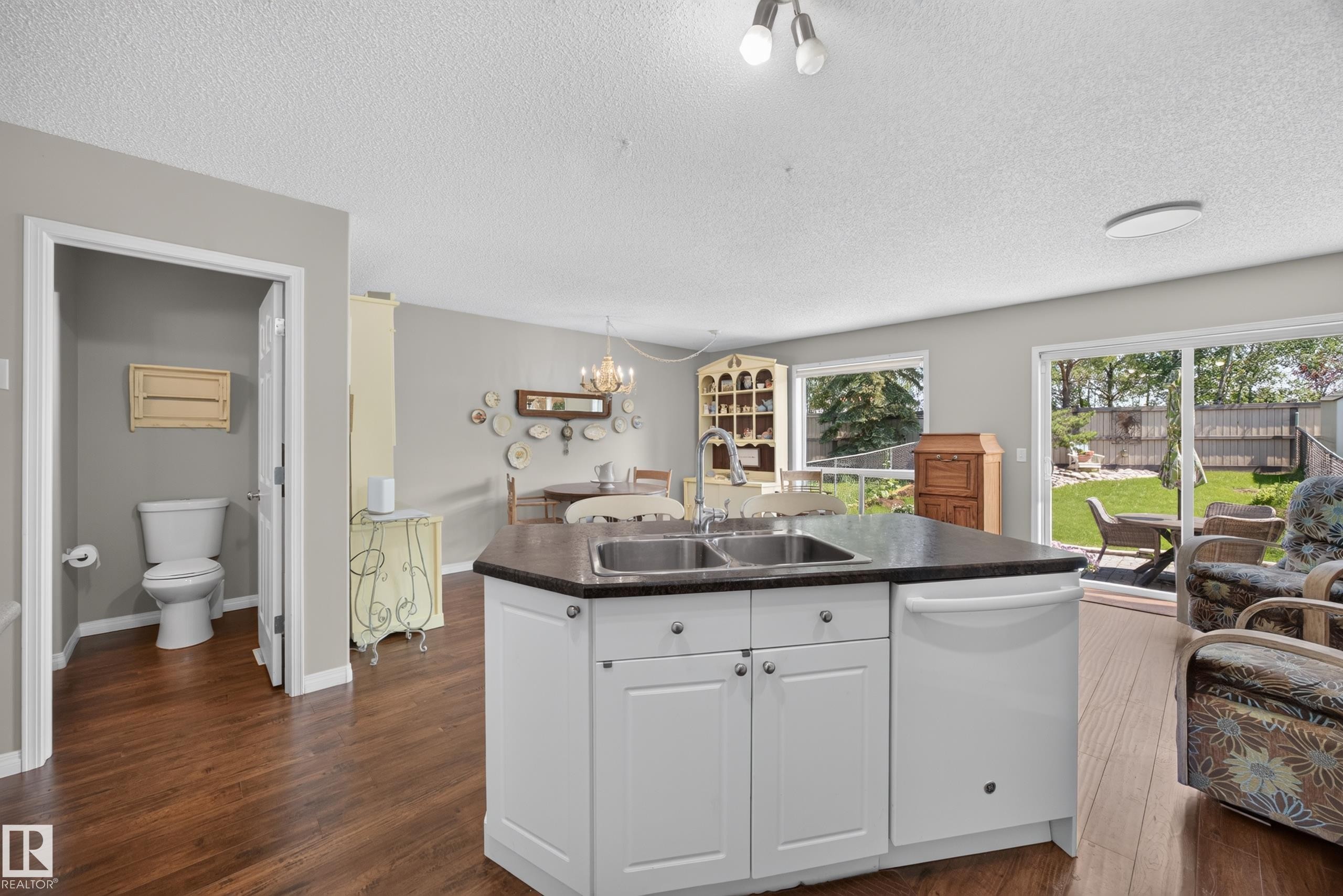 Kitchen island with white cabinetry, a double basin sink, and a dark countertop - #7 155 Crocus Cr, Sherwood Park, AB - Indoor Photo Showing Kitchen With Double Sink