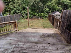 Spacious composite deck with wood-finish flooring overlooking a private, tree-lined yard with mature landscaping and wooden privacy fencing on both sides -