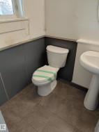 White pedestal sink, ceramic tile flooring, and a white toilet -