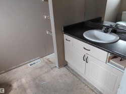 Vanity with integrated basin, dark countertop, and base cabinetry with dark hardware -