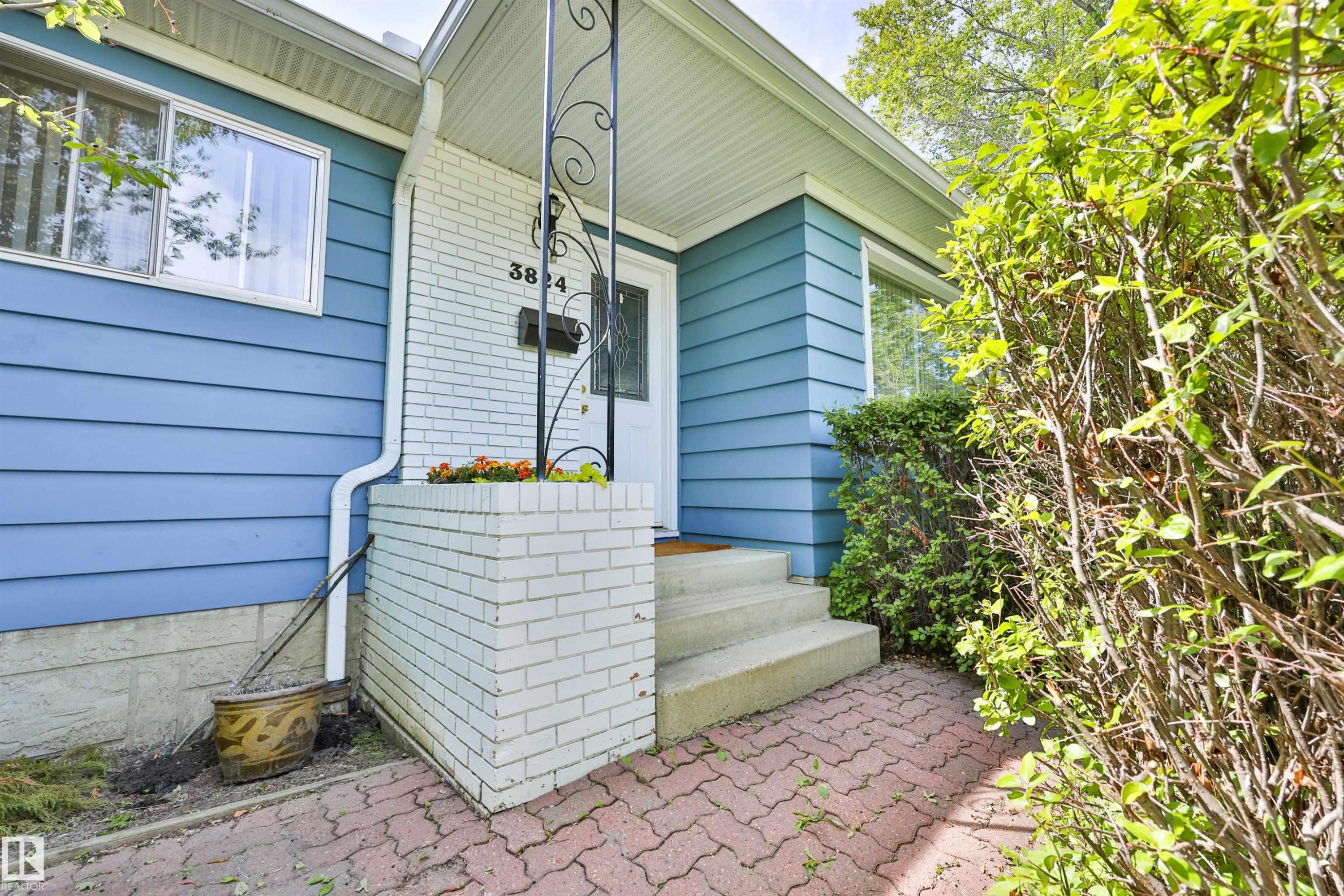 Front entrance featuring a concrete porch, white brick accents, and a wrought iron support column - 3824 111B Street Nw, Edmonton, AB - Outdoor