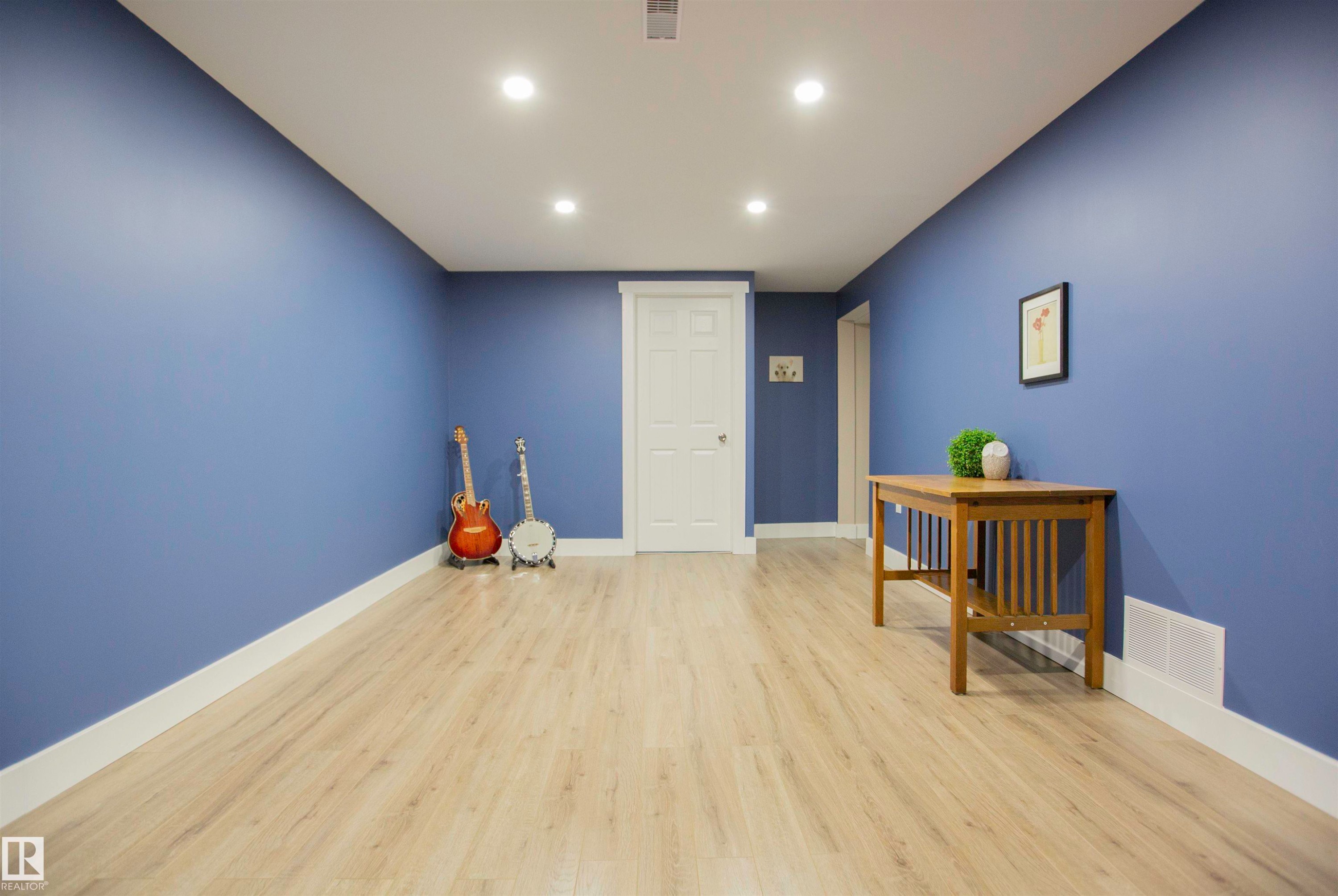 Spacious room with striking periwinkle walls, recessed ceiling lighting, and light wood-finish flooring throughout - 9107 58 Street Nw, Edmonton, AB - Indoor Photo Showing Other Room