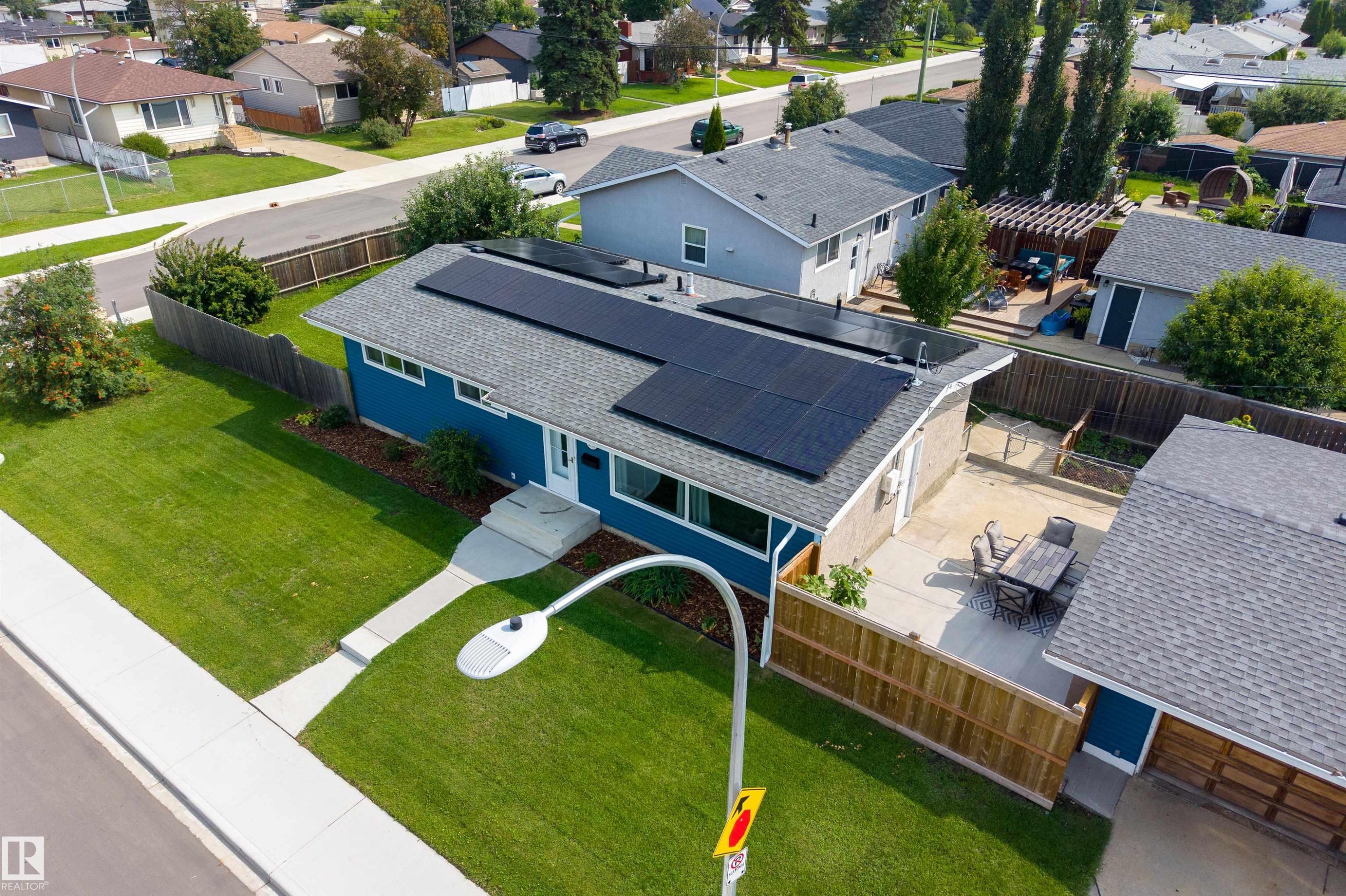 Exterior with solar panels, blue siding, a paved patio, and a fenced yard - 9107 58 Street Nw, Edmonton, AB - Outdoor