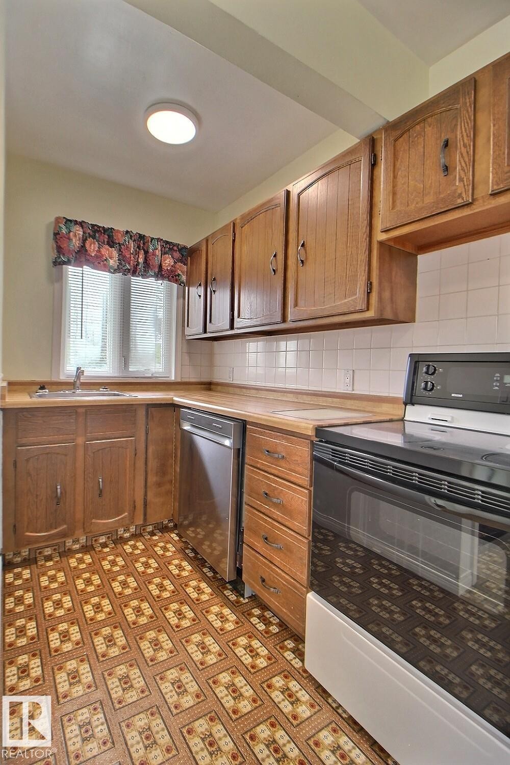 Kitchen featuring wood-finish cabinetry, built-in dishwasher, and a white tile backsplash - 11336 83 Street Nw, Edmonton, AB - Indoor Photo Showing Kitchen