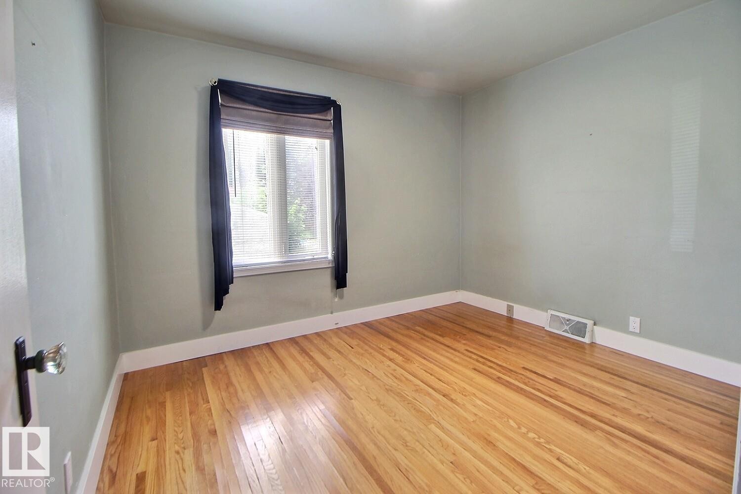 Wood-finish flooring with white trim and light-toned walls - 11336 83 Street Nw, Edmonton, AB - Indoor Photo Showing Other Room