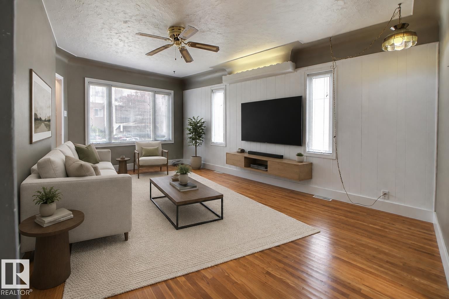 Bay window with multiple panes, wood-finish flooring, ceiling fan with integrated lighting, recessed lighting, and a floating media console - 11336 83 Street Nw, Edmonton, AB - Indoor Photo Showing Living Room