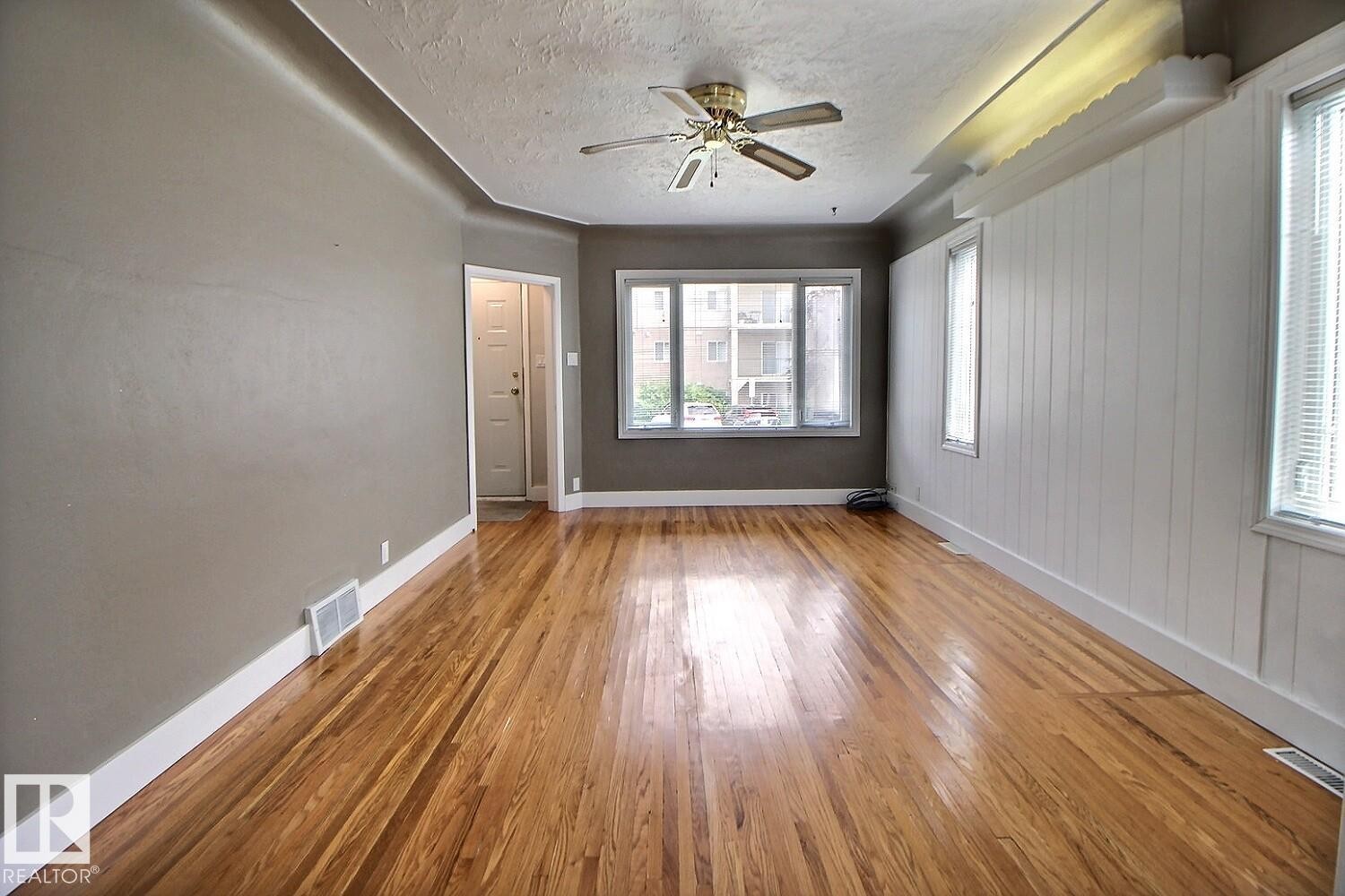 Hardwood flooring, painted walls, white trim, multiple windows with blinds, and a ceiling fan - 11336 83 Street Nw, Edmonton, AB - Indoor Photo Showing Other Room