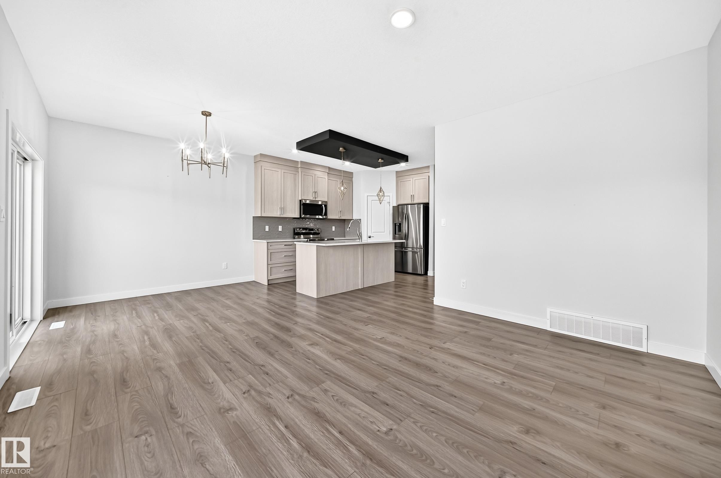 Open-concept living space featuring wood-finish flooring, a modern chandelier, and recessed lighting - 8823 Carson Way Sw, Edmonton, AB - Indoor Photo Showing Kitchen