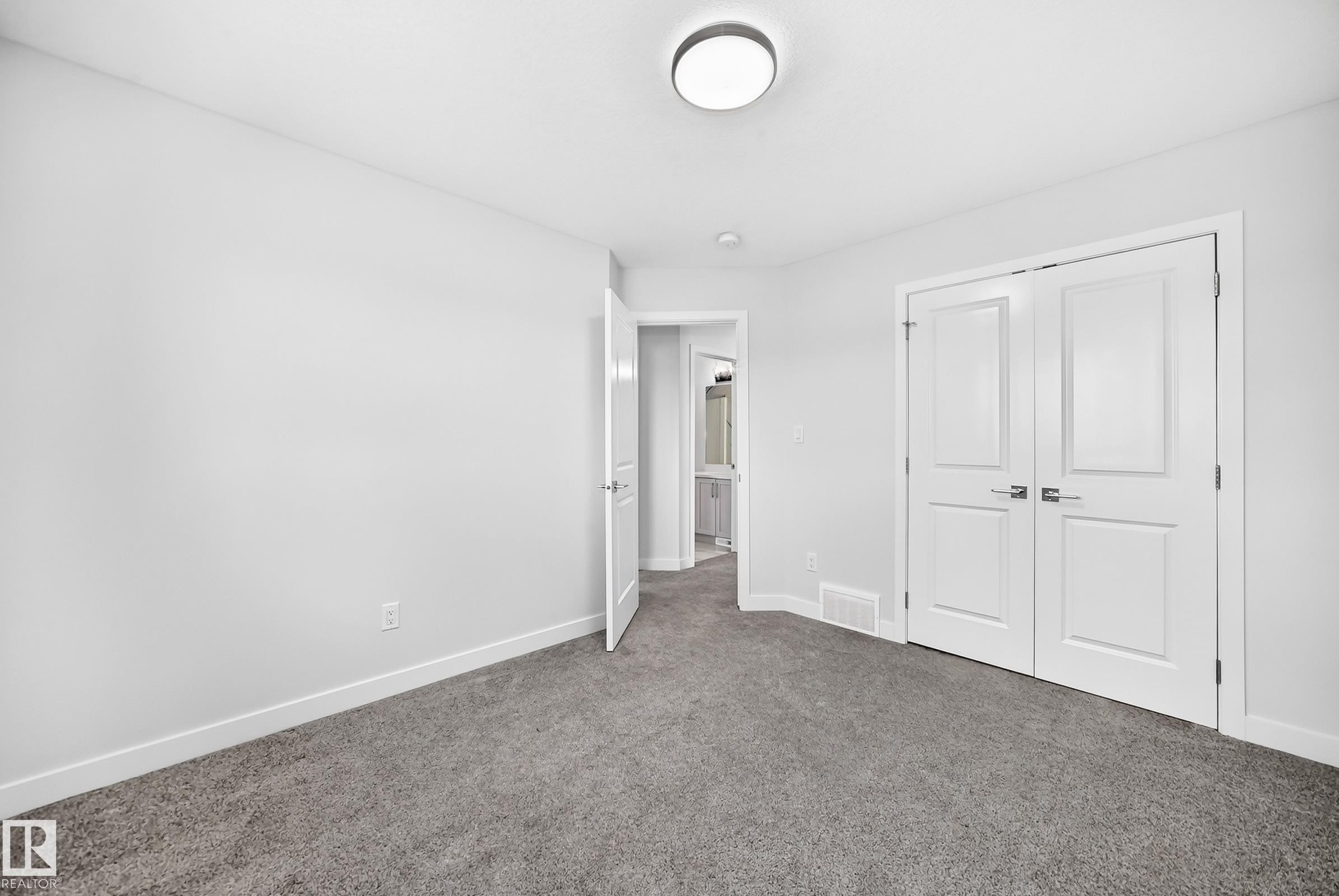 Soft gray carpeting, white painted walls, and a contemporary flush-mount ceiling light - 8823 Carson Way Sw, Edmonton, AB - Indoor Photo Showing Other Room