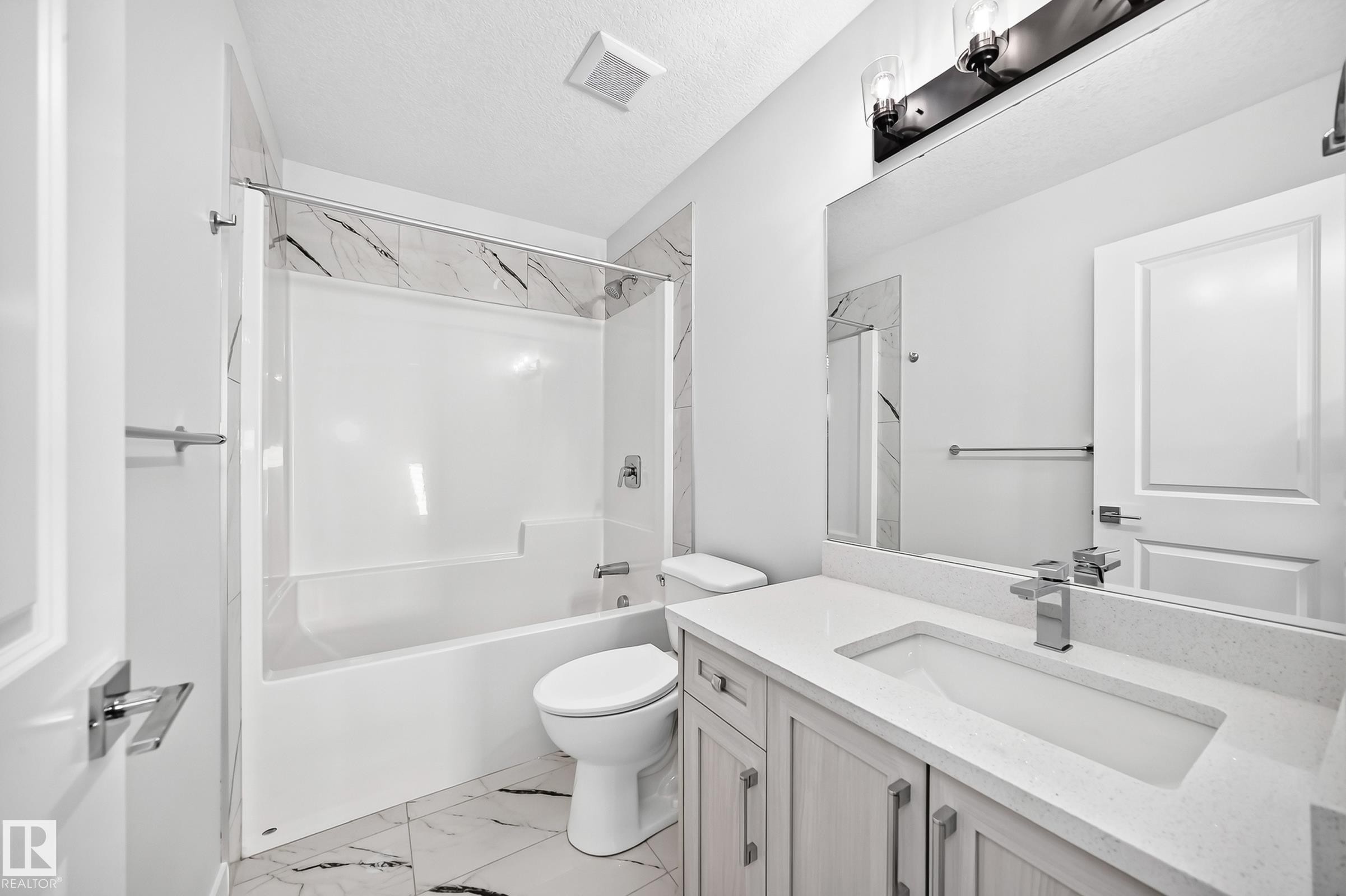 White vanity with integrated sink and chrome faucet, large frameless mirror, and overhead vanity lighting - 8823 Carson Way Sw, Edmonton, AB - Indoor Photo Showing Bathroom