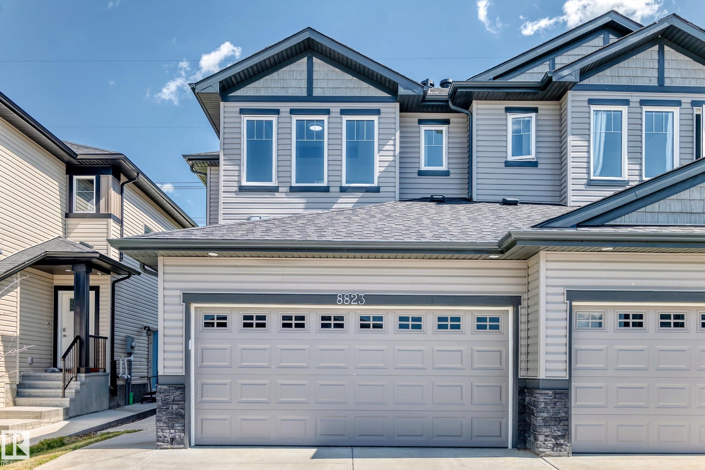 Light-colored siding with dark trim, two-car garage, multiple windows, and a covered entry - 8823 Carson Way Sw, Edmonton, AB - Outdoor With Facade