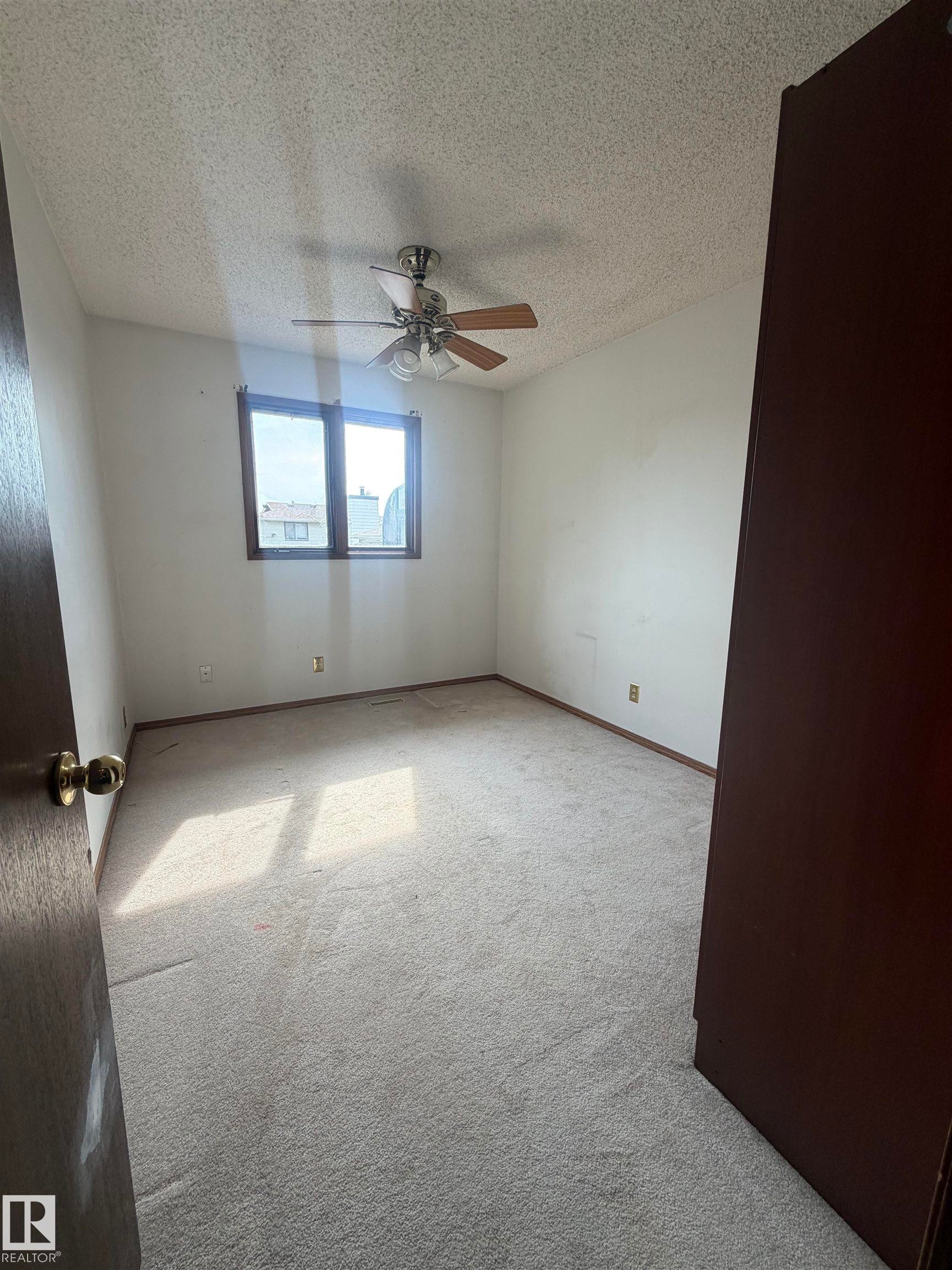 Bright bedroom featuring neutral carpeting, ceiling fan with integrated lighting, and large window with natural light - 9223 172 Avenue Nw, Edmonton, AB