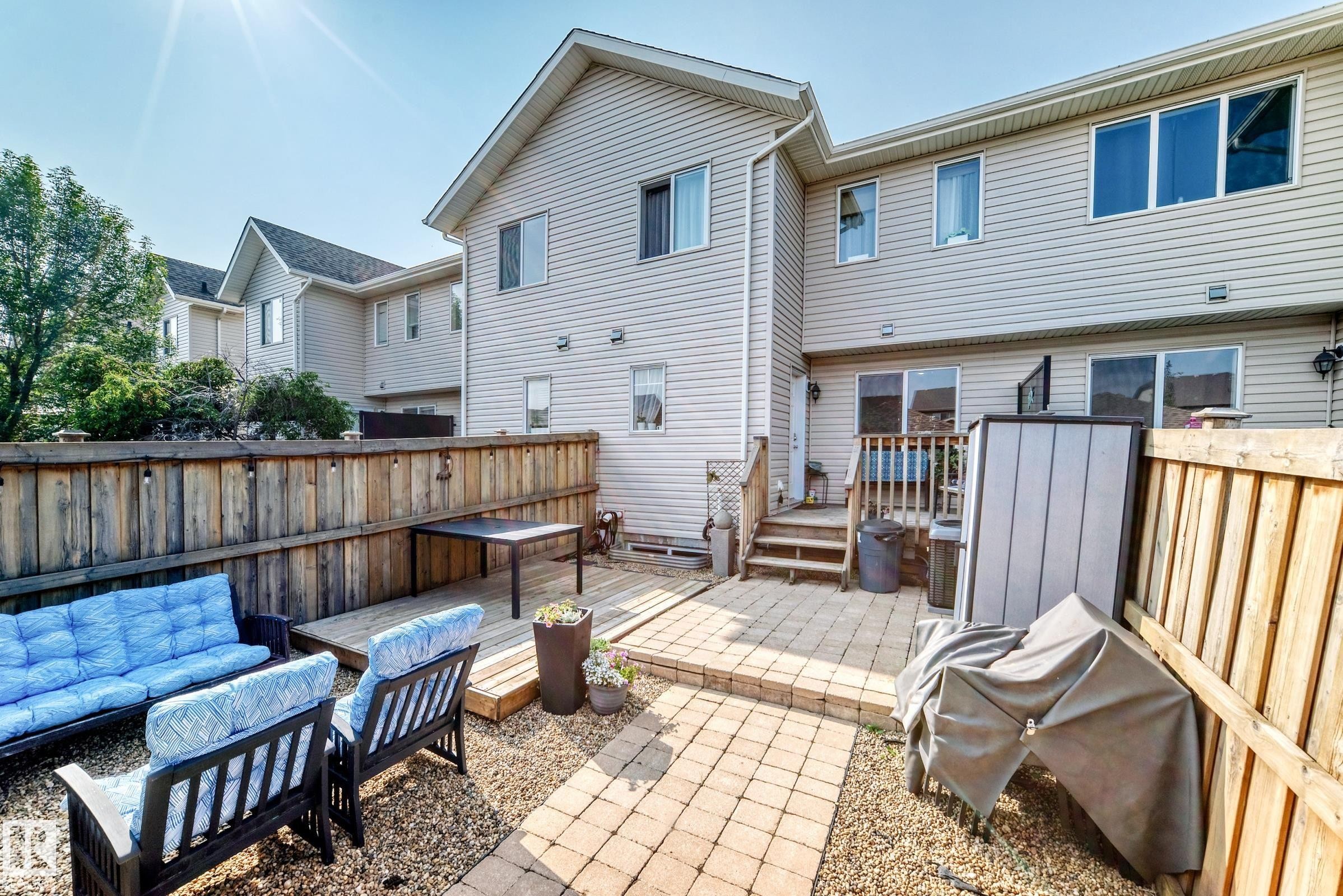 Fenced backyard featuring a paver patio, gravel landscaping, a raised wood deck, and an exterior staircase leading to the residence - 466 Chappelle Drive Sw, Edmonton, AB - Outdoor With Deck Patio Veranda With Exterior