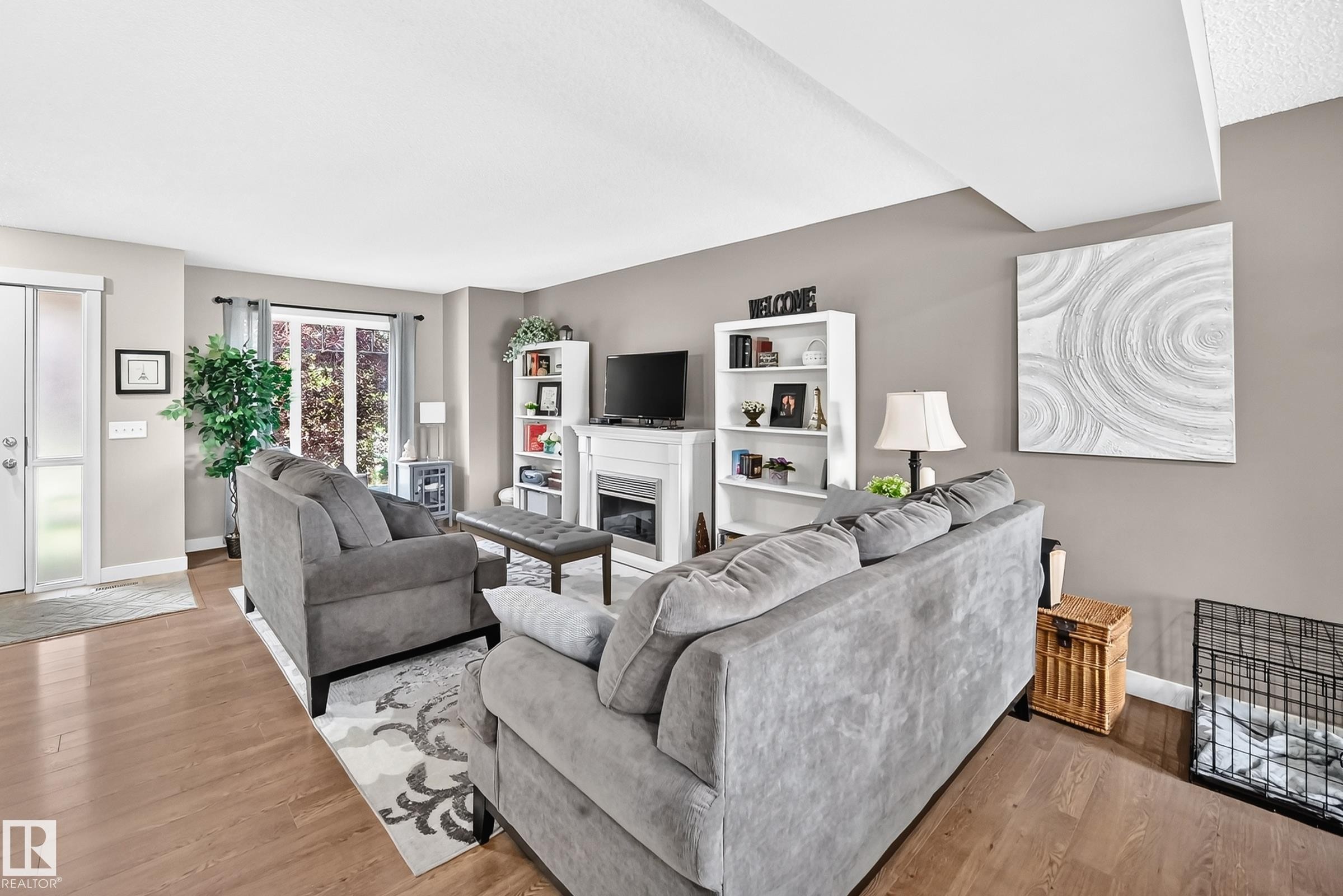 Open-concept living area with wood-finish flooring, a white-framed fireplace, and built-in shelving - 466 Chappelle Drive Sw, Edmonton, AB - Indoor Photo Showing Living Room With Fireplace