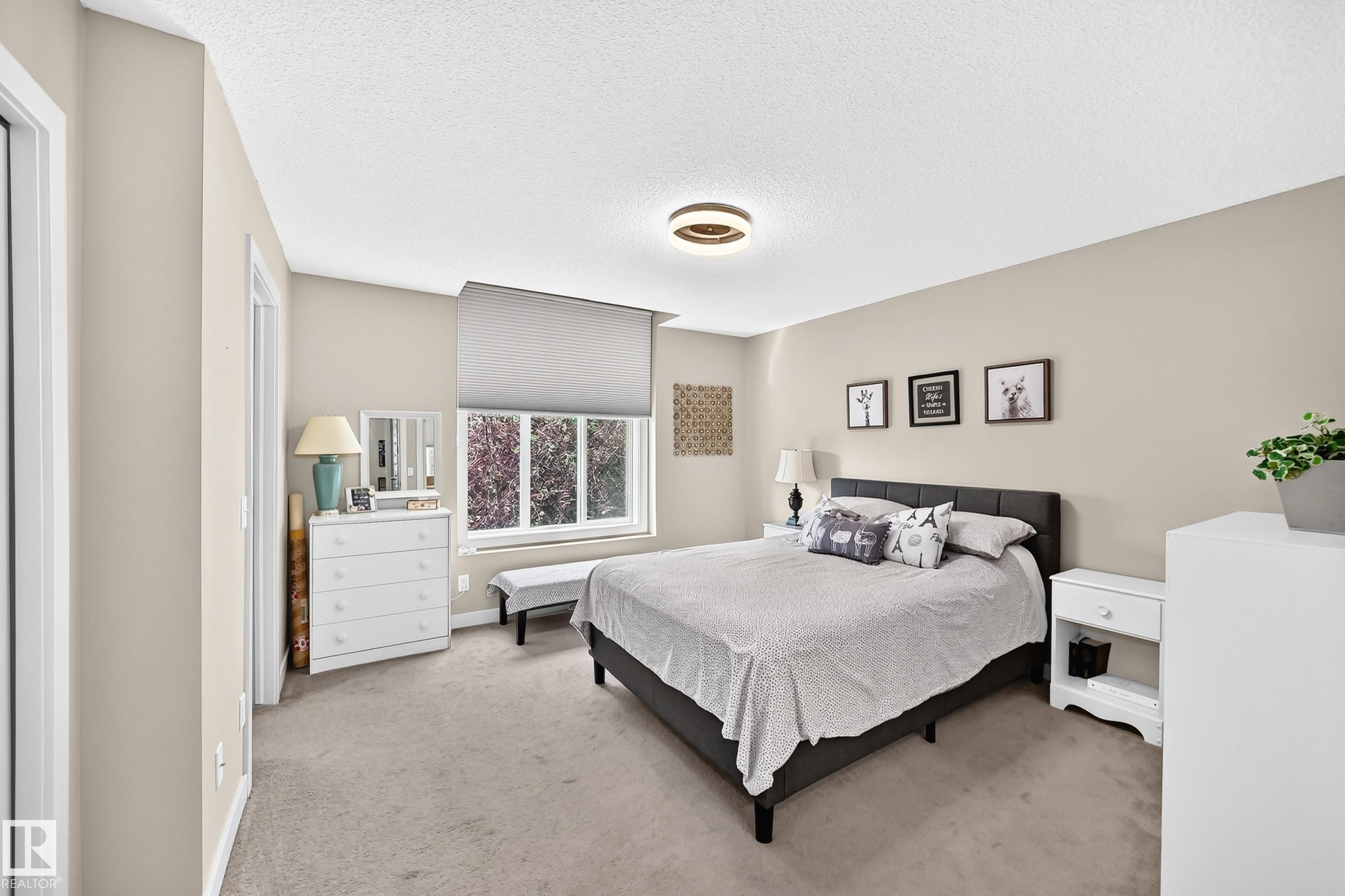 Carpeted room featuring a large window, a built-in closet, a white dresser, and a ceiling-mounted light fixture - 466 Chappelle Drive Sw, Edmonton, AB - Indoor Photo Showing Bedroom