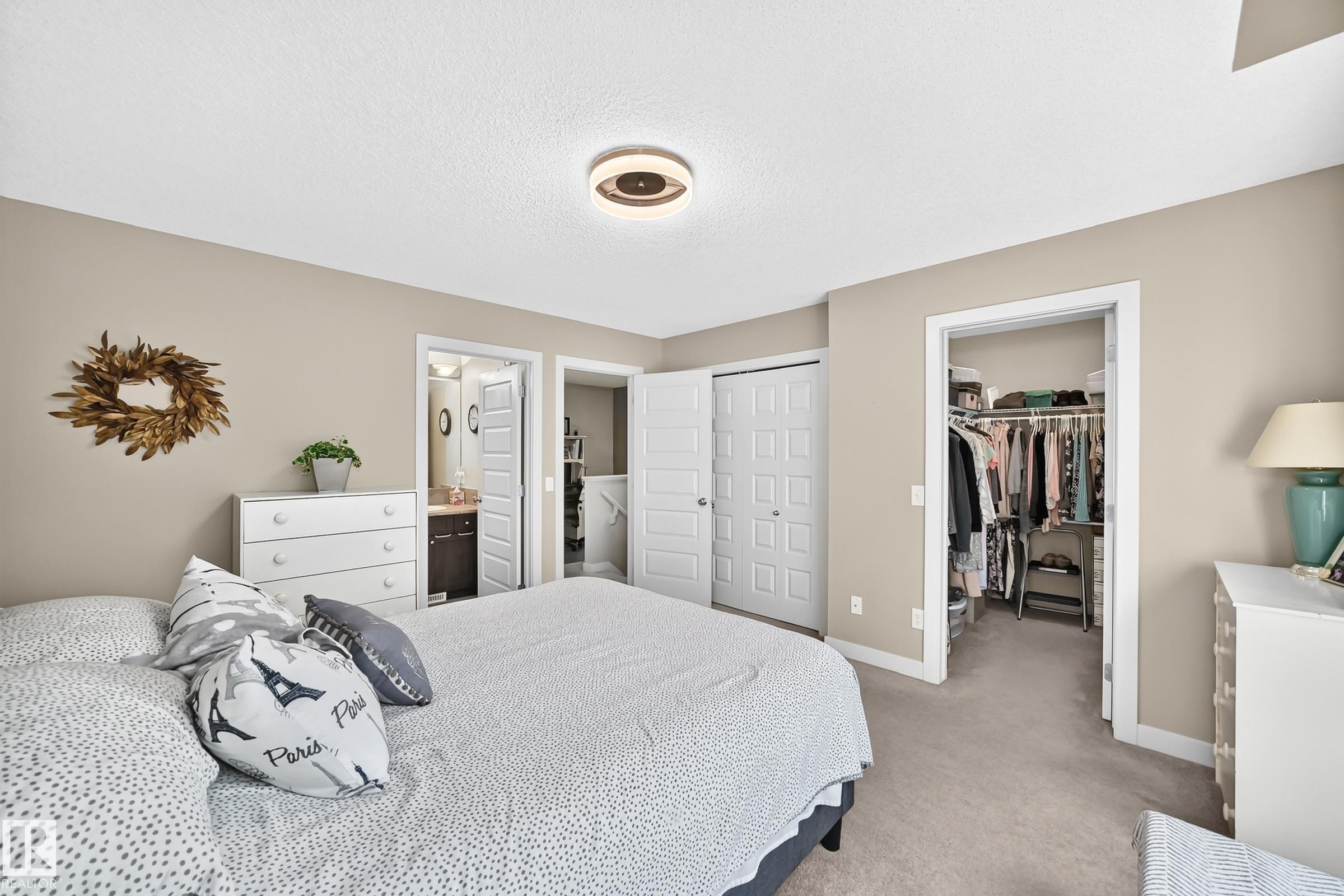 Bedroom featuring neutral wall colors, light-colored carpeting, a contemporary ceiling light fixture, a closet with bifold doors, and an additional walk-in closet - 466 Chappelle Drive Sw, Edmonton, AB - Indoor Photo Showing Bedroom