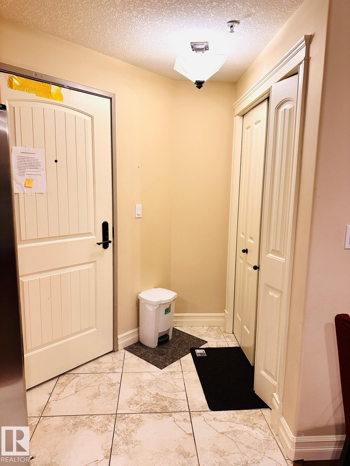 Tile flooring, paneled interior door, and overhead light fixture - #207 10142 111 St Nw, Edmonton, AB - Indoor