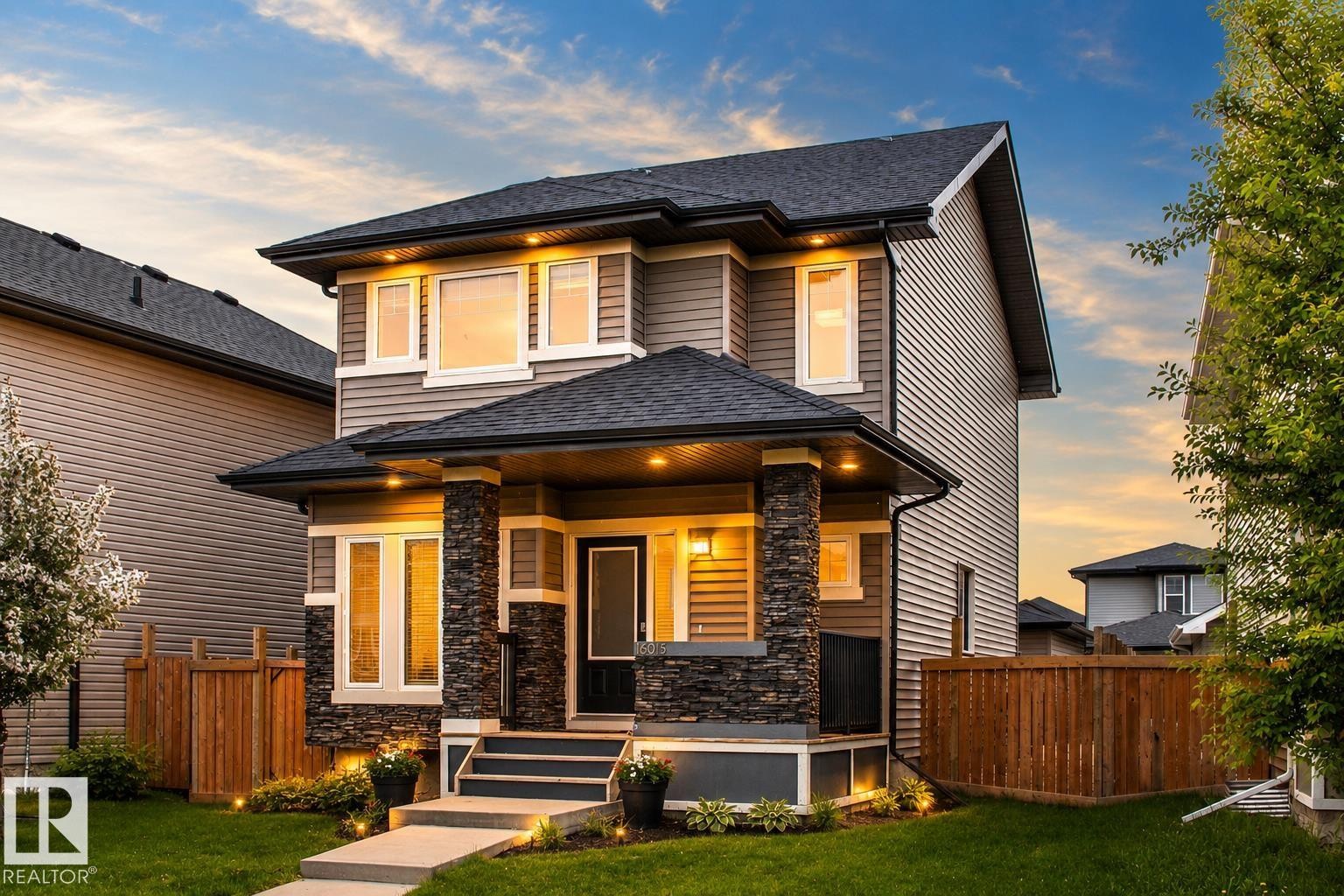 Two-story home with stone column accents, neutral-toned siding, and a dark shingle roof - 16015 11 Avenue Sw, Edmonton, AB - Outdoor