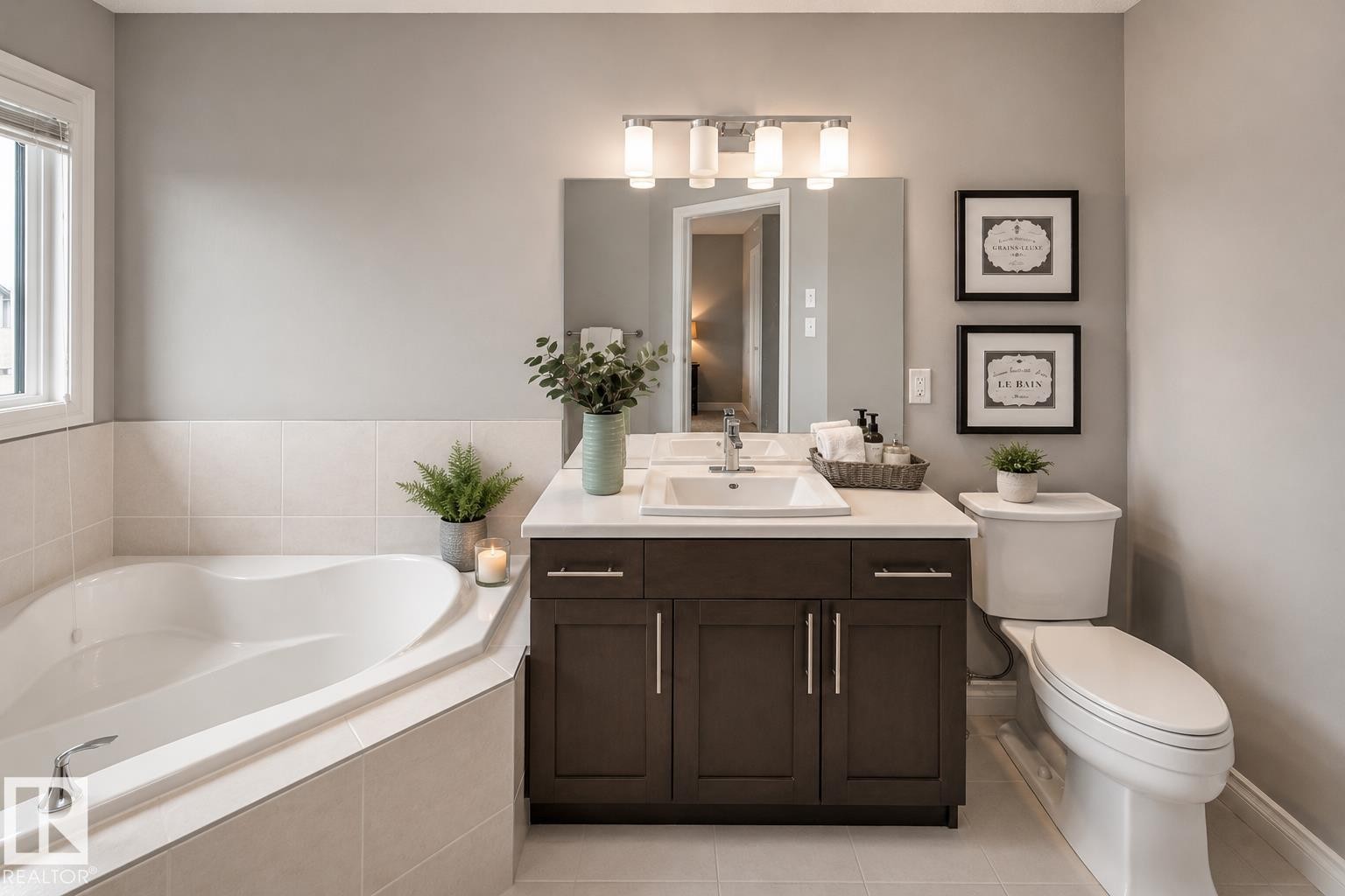 Corner soaking tub with tiled surround, single vanity with integrated sink, dark wood-finish cabinetry, and overhead vanity lighting - 16015 11 Avenue Sw, Edmonton, AB - Indoor Photo Showing Bathroom