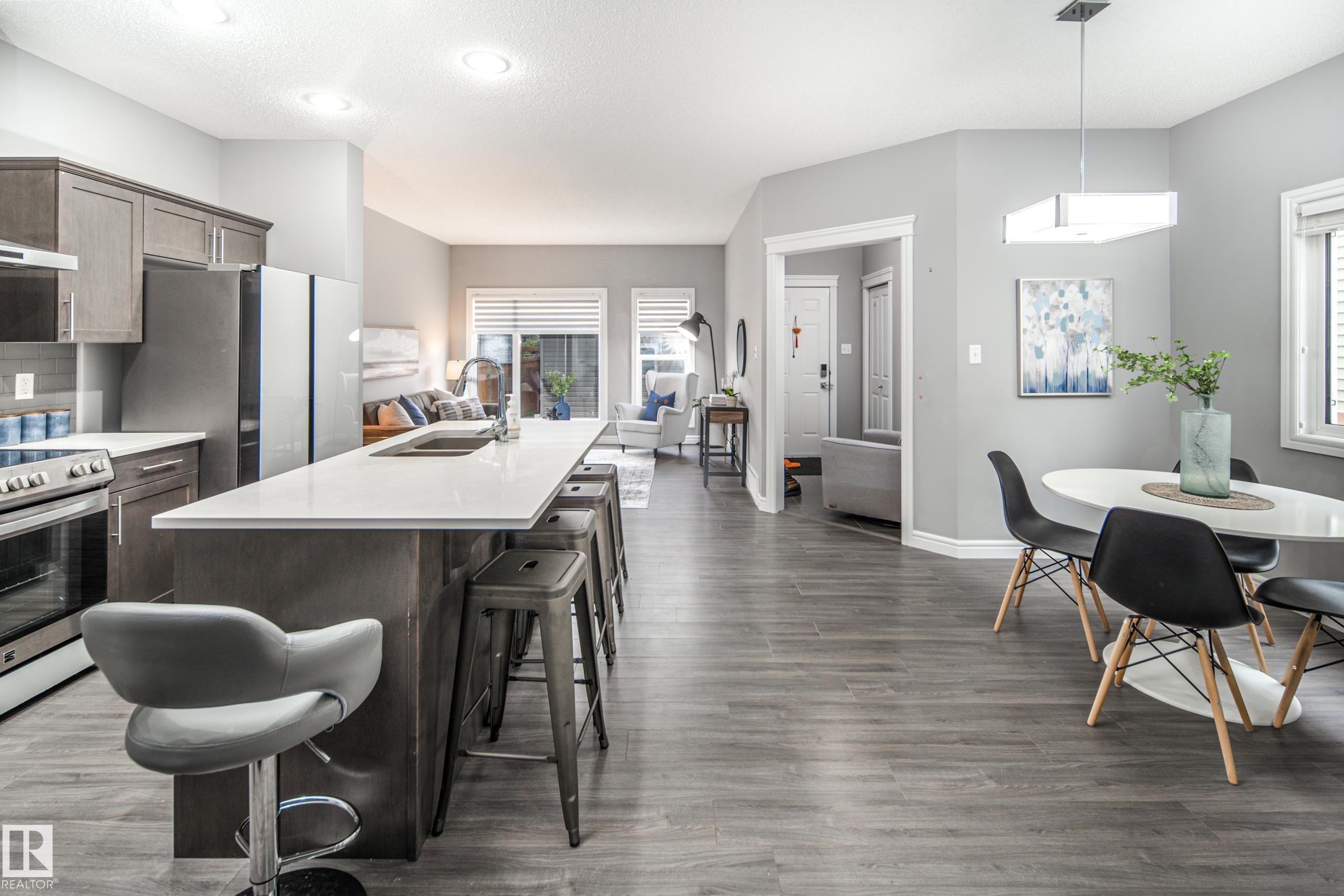 Open-concept living area featuring wood-finish flooring, a kitchen island with seating, stainless steel appliances, and recessed lighting - 16015 11 Avenue Sw, Edmonton, AB - Indoor