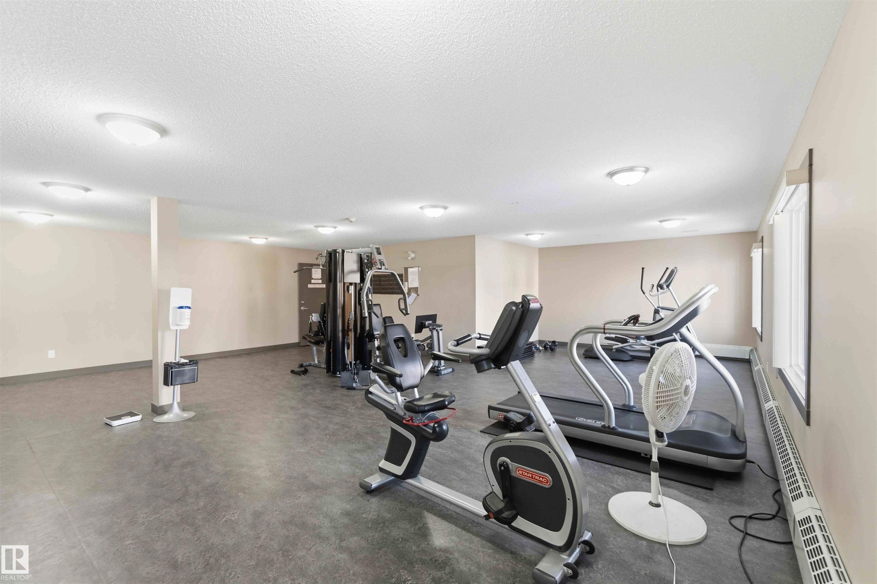 Dedicated fitness area featuring durable dark flooring, multiple windows, and recessed ceiling lighting - #114 2207 44 Av Nw, Edmonton, AB - Indoor Photo Showing Gym Room