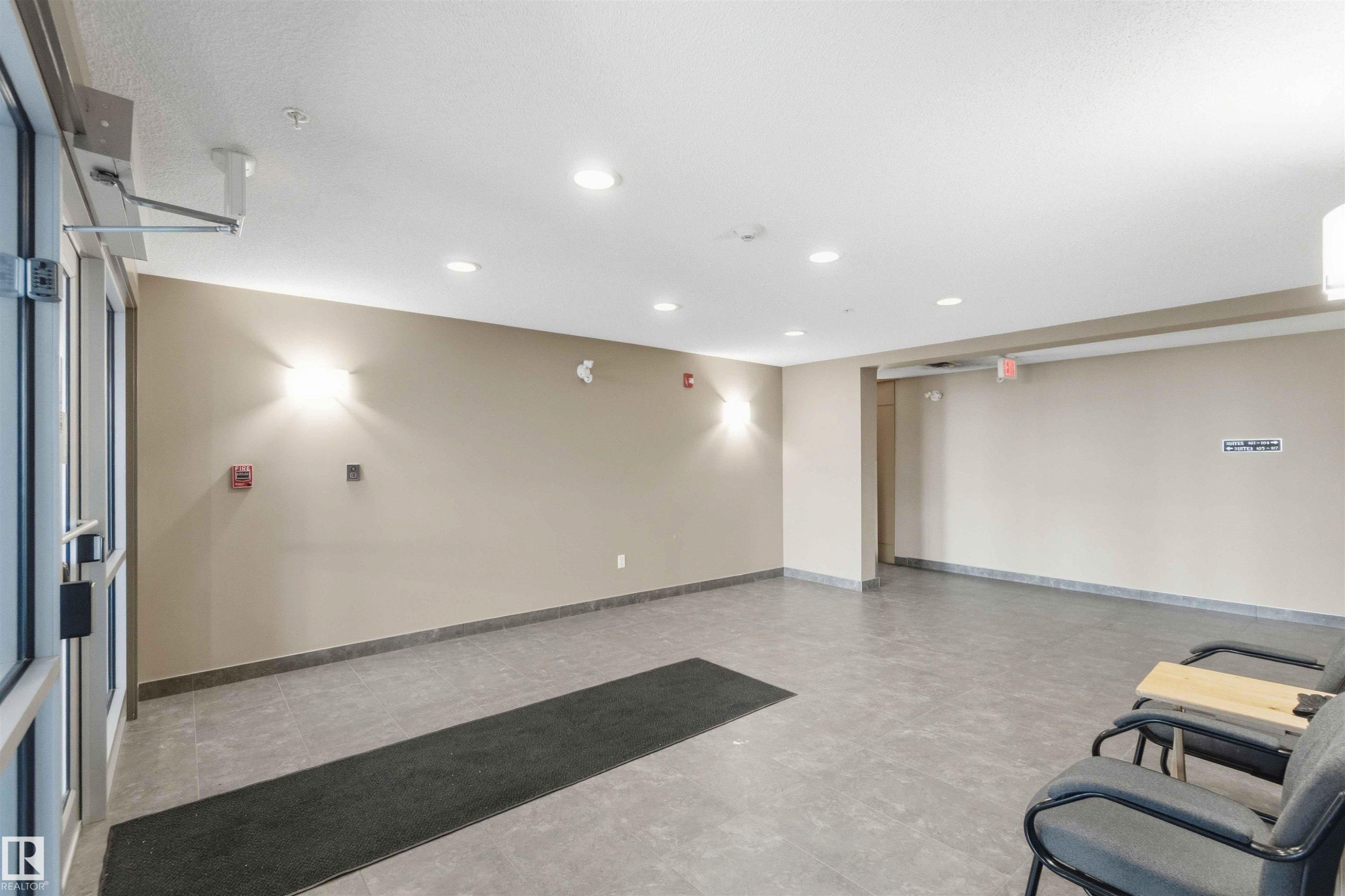 Spacious common area featuring durable tile flooring, recessed ceiling lighting, and contemporary wall sconces - #114 2207 44 Av Nw, Edmonton, AB - Indoor Photo Showing Other Room