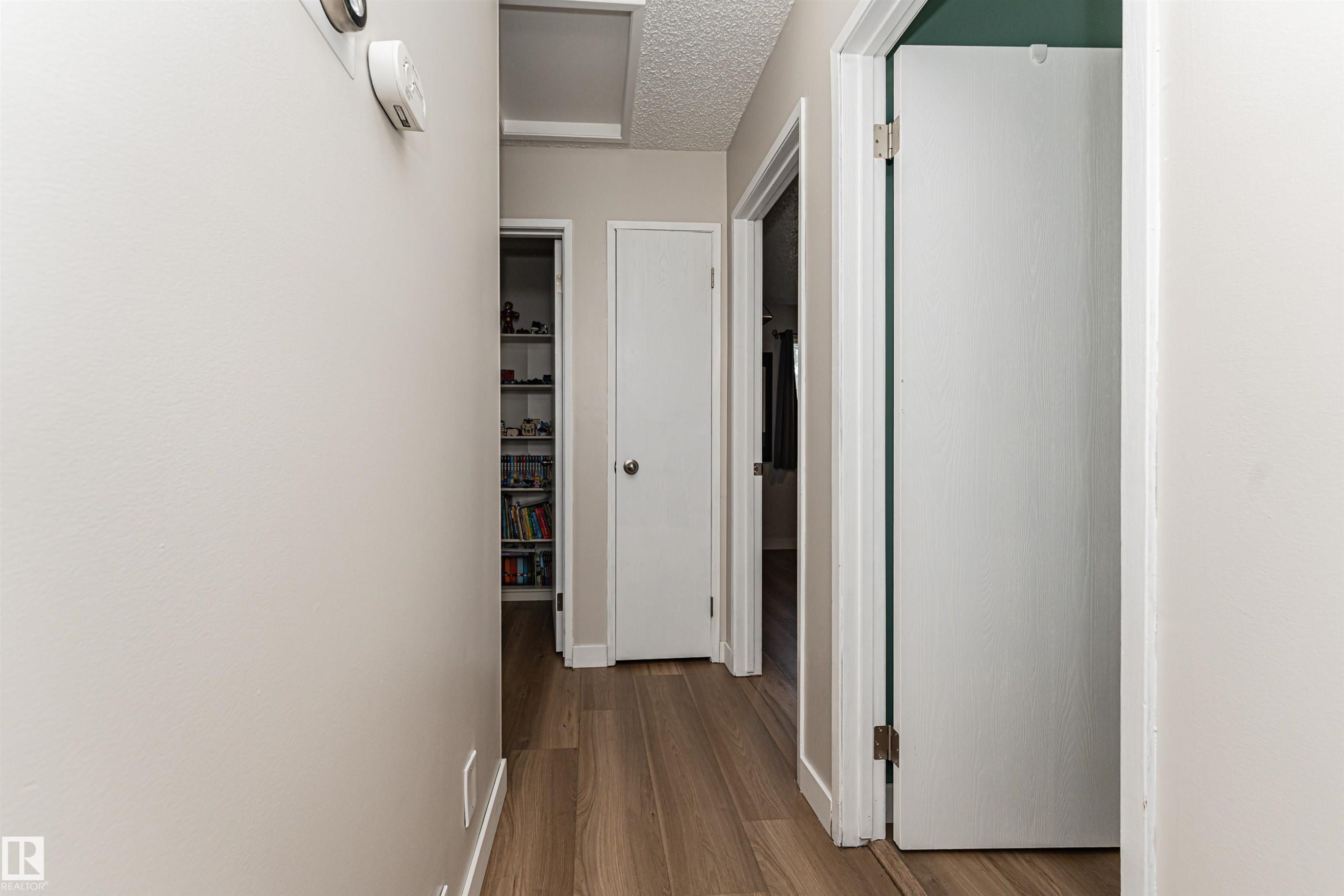 Hallway with wood-finish flooring, white painted walls, and multiple doorways - 4521 29 Avenue Nw, Edmonton, AB - Indoor Photo Showing Other Room