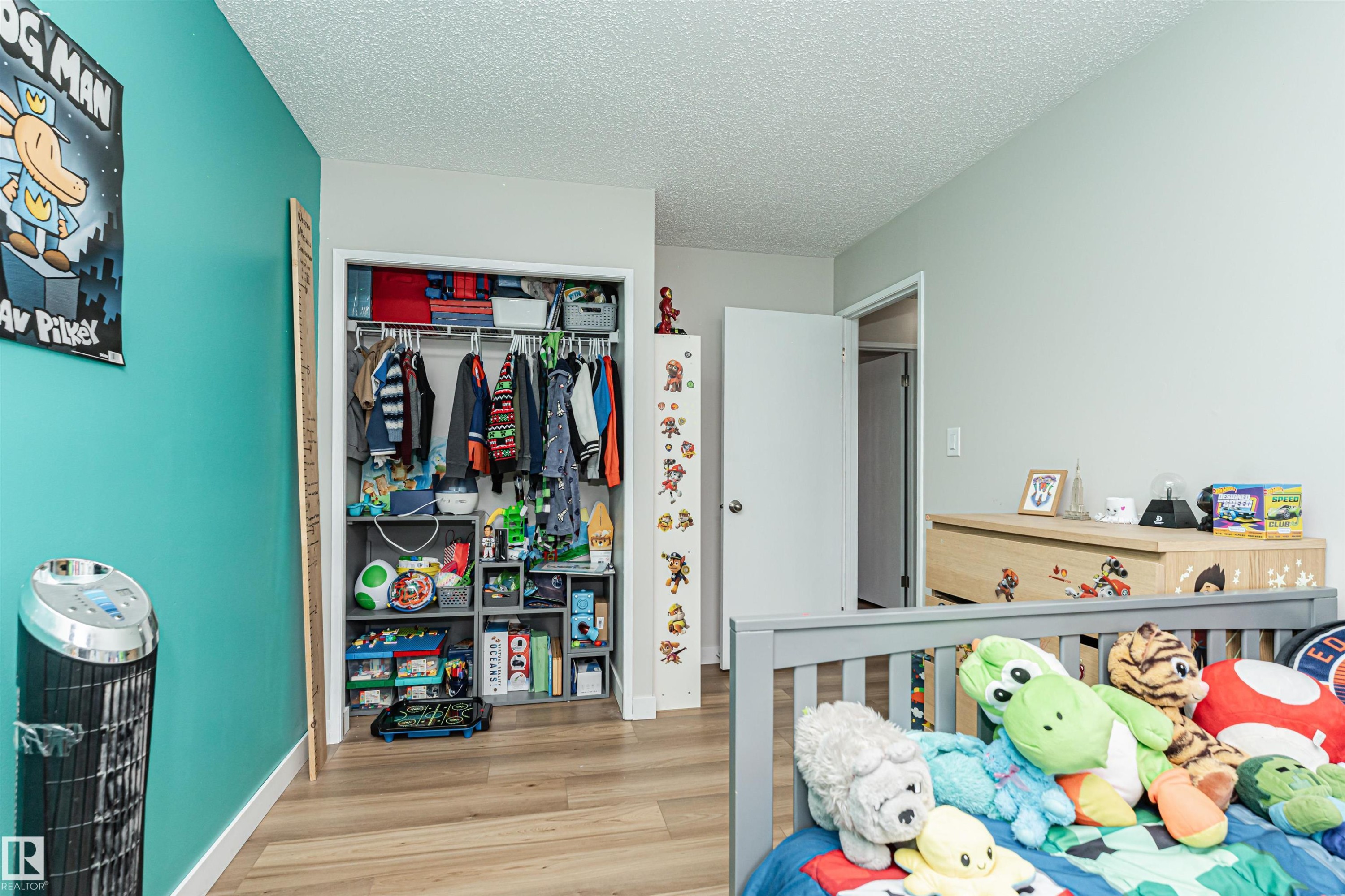 Wood-finish flooring with a contrasting accent wall - 4521 29 Avenue Nw, Edmonton, AB - Indoor Photo Showing Other Room