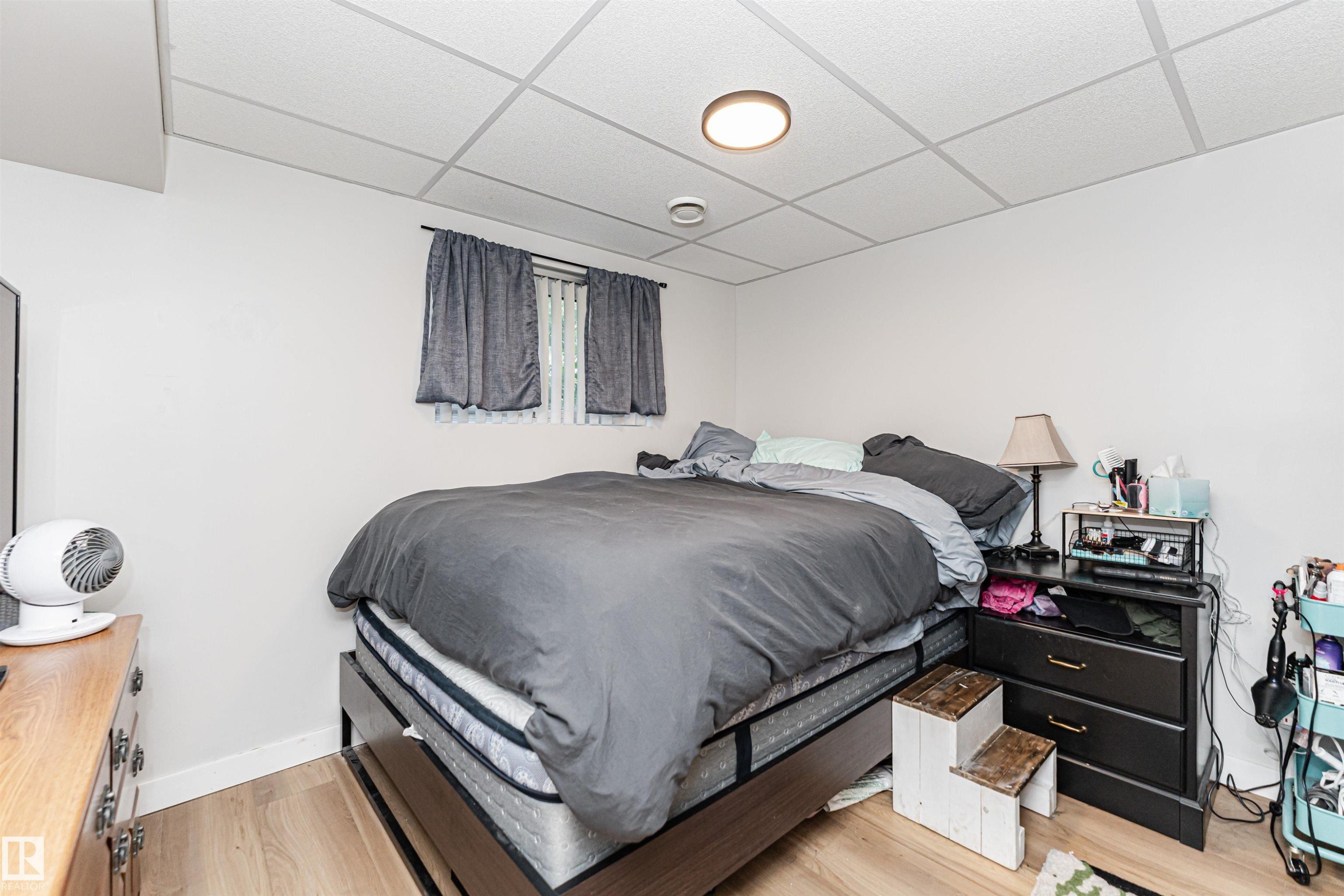 Wood-finish flooring with white walls and a drop ceiling - 4521 29 Avenue Nw, Edmonton, AB - Indoor Photo Showing Bedroom