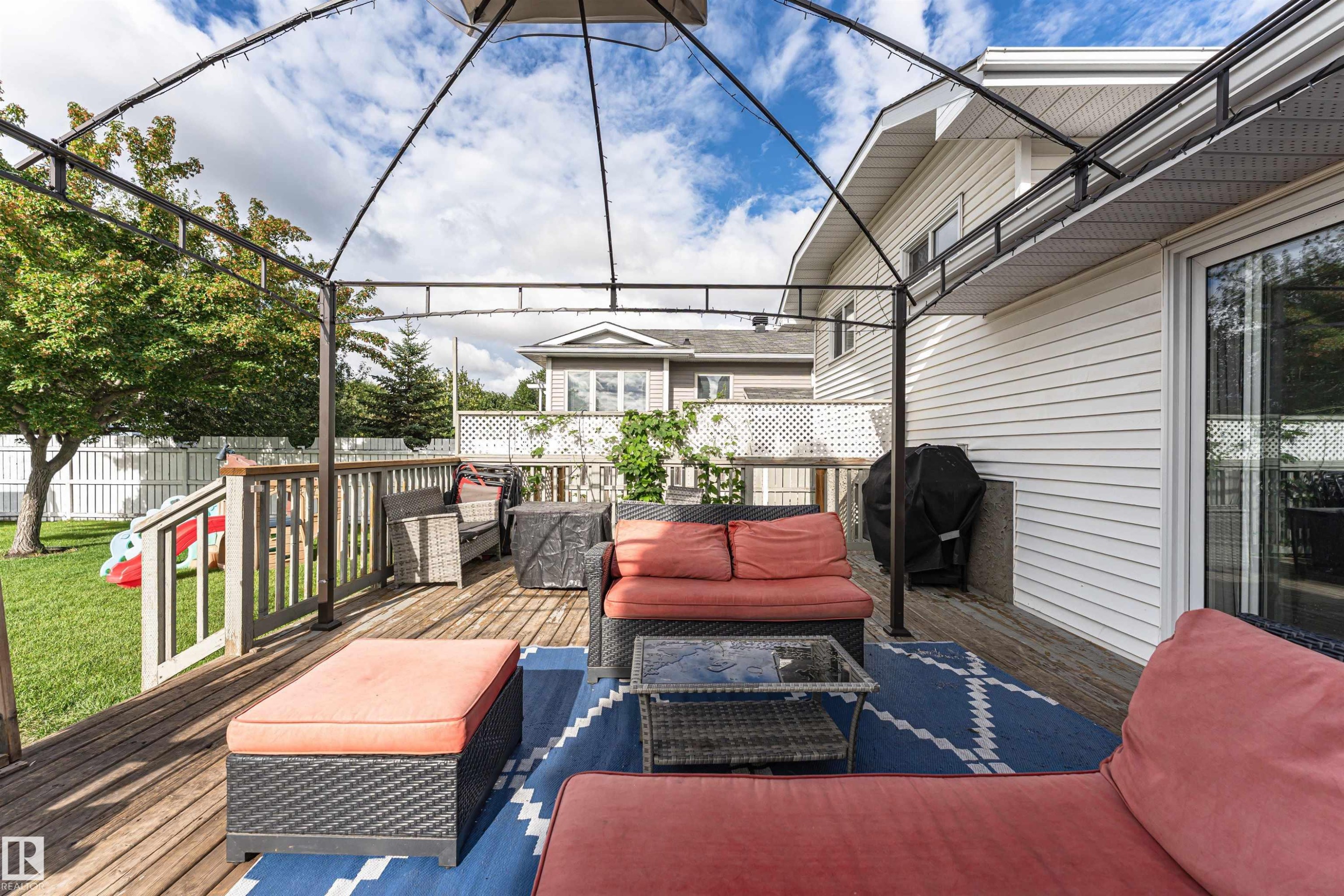 Expansive outdoor deck with a metal gazebo frame, white siding, and sliding glass doors - 4521 29 Avenue Nw, Edmonton, AB - Outdoor With Deck Patio Veranda With Exterior