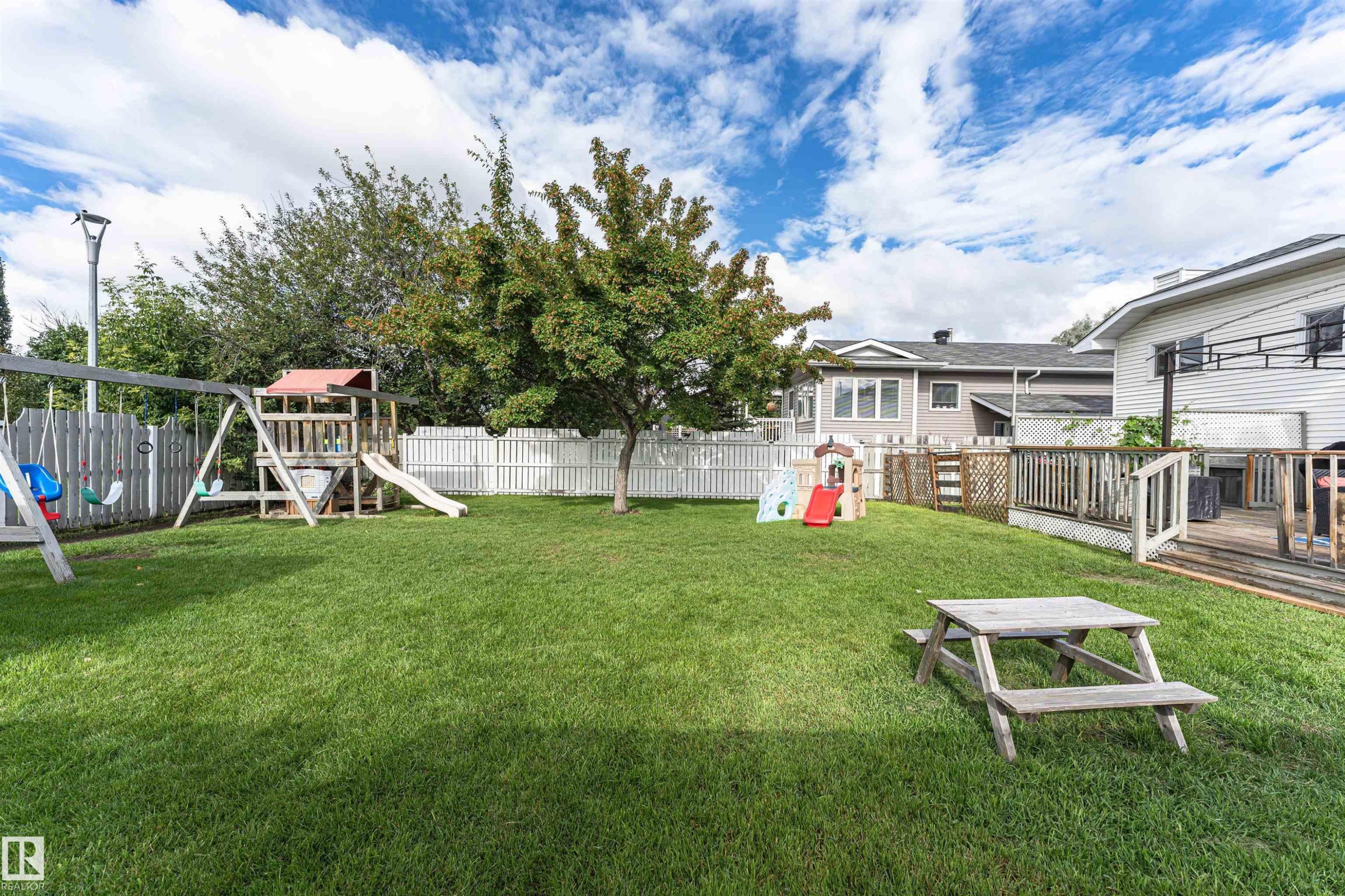 Expansive backyard featuring a large green lawn, mature trees, and a perimeter fence - 4521 29 Avenue Nw, Edmonton, AB - Outdoor With Backyard