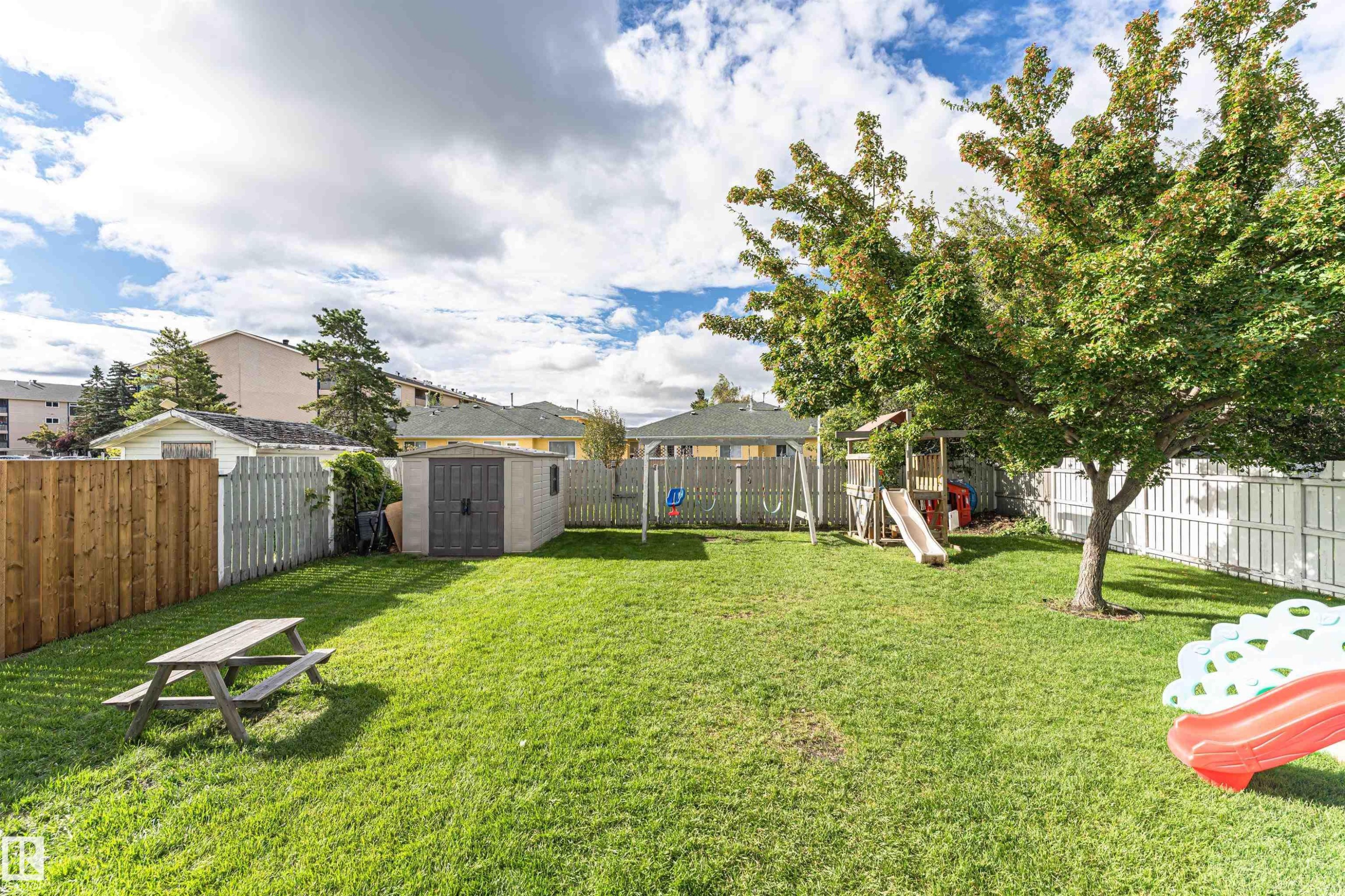 Expansive lawn area with a mature tree, privacy fencing, and a storage shed - 4521 29 Avenue Nw, Edmonton, AB - Outdoor With Backyard