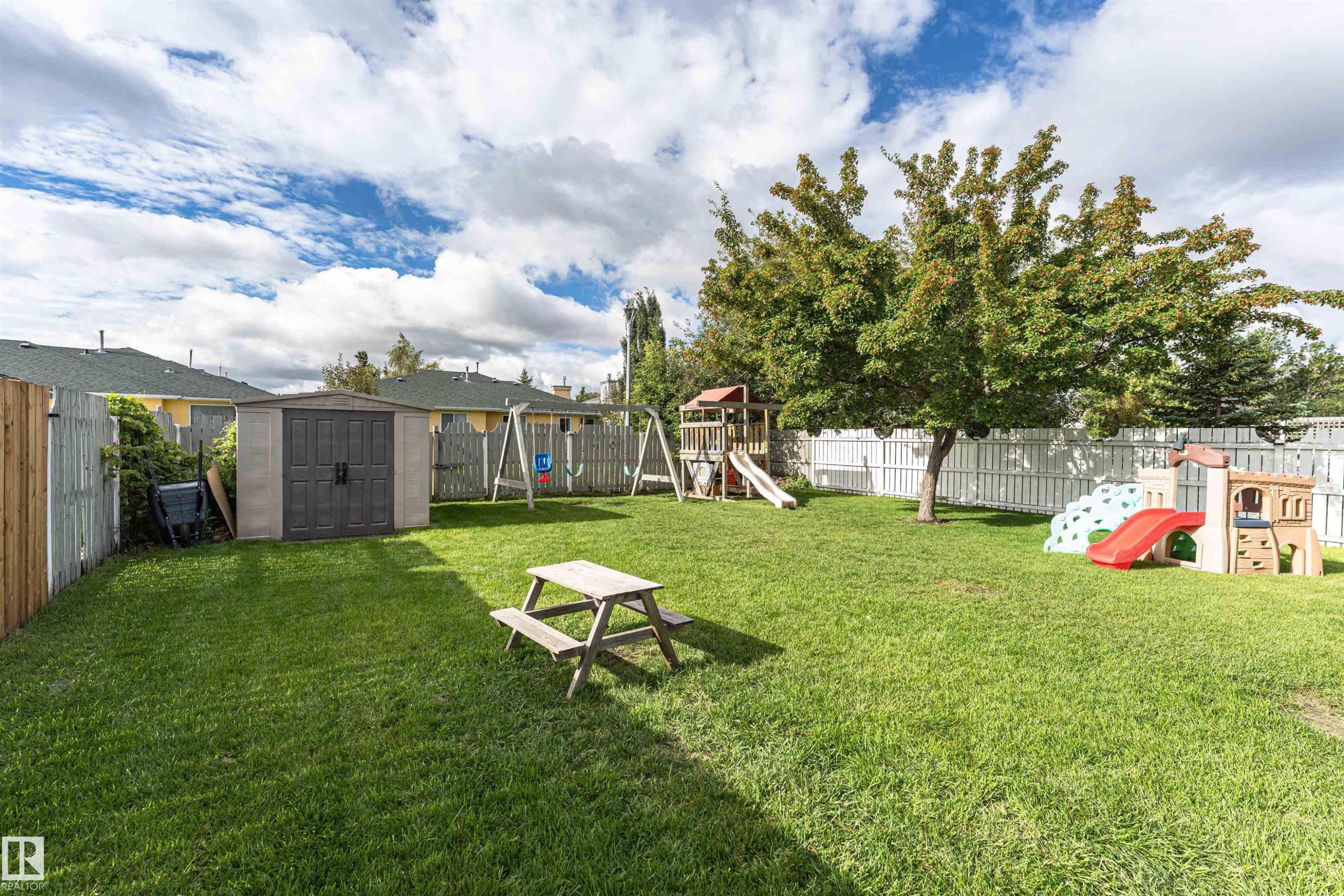 Expansive backyard featuring a manicured lawn, established trees, and a storage shed - 4521 29 Avenue Nw, Edmonton, AB - Outdoor