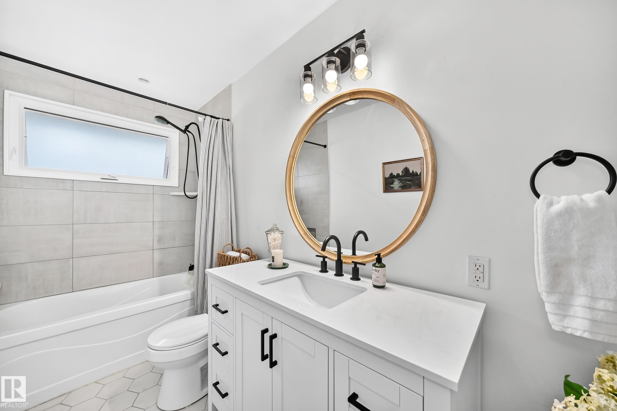 White vanity with integrated sink, black fixtures, and round gold-framed mirror - 16406 87A Avenue Nw, Edmonton, AB - Indoor Photo Showing Bathroom