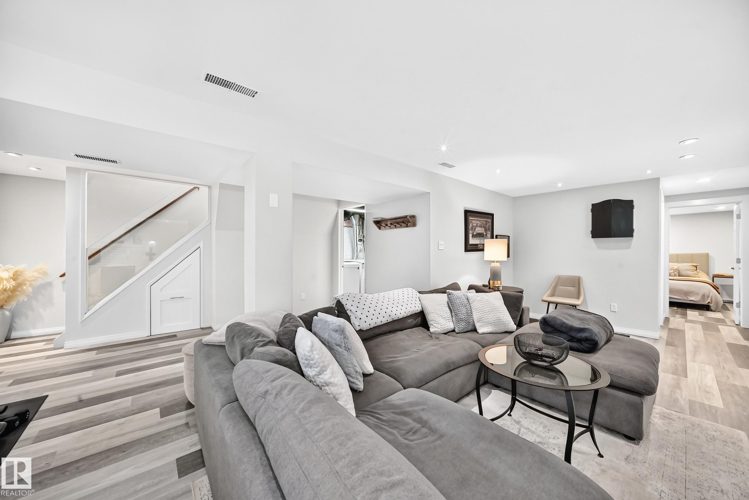 Spacious living area featuring recessed lighting, wood-finish flooring, a built-in staircase with storage, and an open doorway to an additional room - 16406 87A Avenue Nw, Edmonton, AB - Indoor Photo Showing Living Room