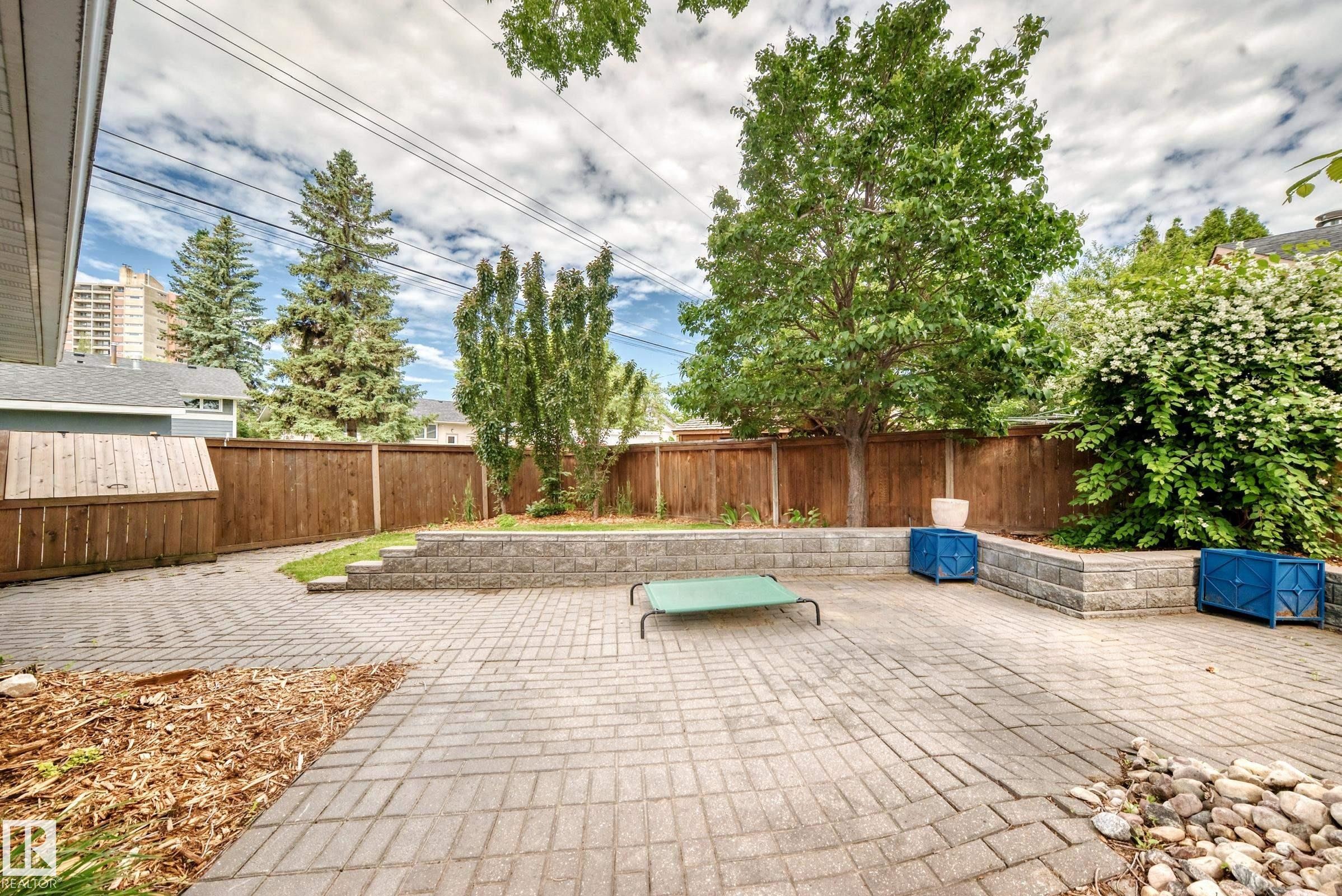 Paved patio area featuring brick-patterned pavers and a wood privacy fence - 16406 87A Avenue Nw, Edmonton, AB - Outdoor With Deck Patio Veranda