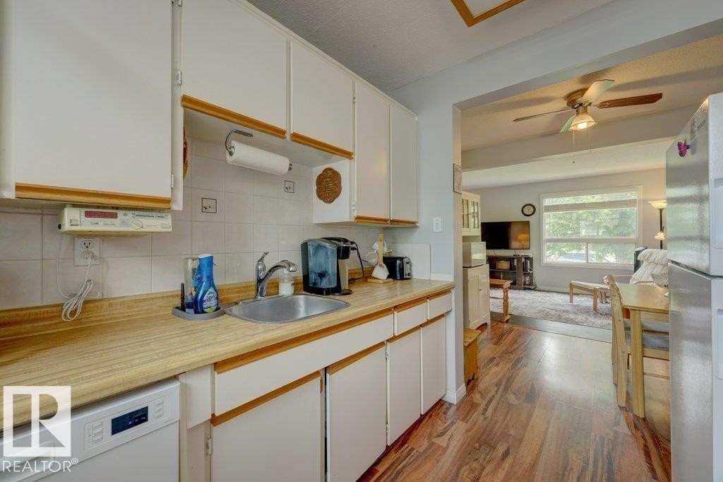 Kitchen featuring white cabinetry, wood-finish countertops, tile backsplash, and stainless steel sink - 307 Northgate Terrace Nw, Edmonton, AB - Indoor Photo Showing Kitchen
