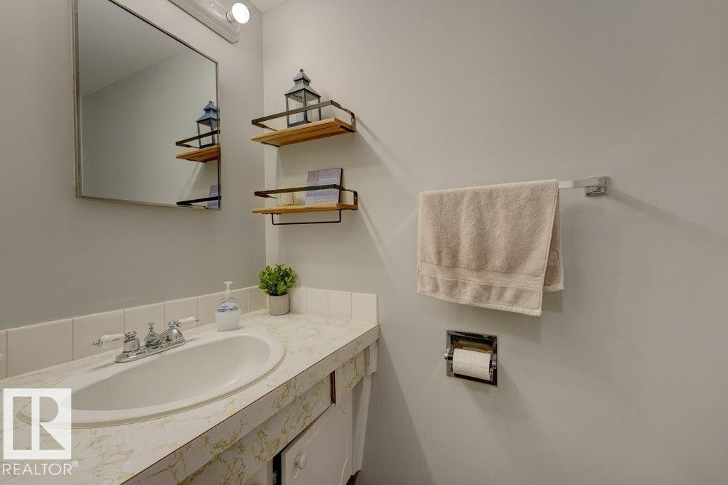 Elegant bathroom featuring a marble-topped vanity with an oval sink, polished chrome faucet, and framed mirror with integrated lighting - 307 Northgate Terrace Nw, Edmonton, AB - Indoor Photo Showing Bathroom