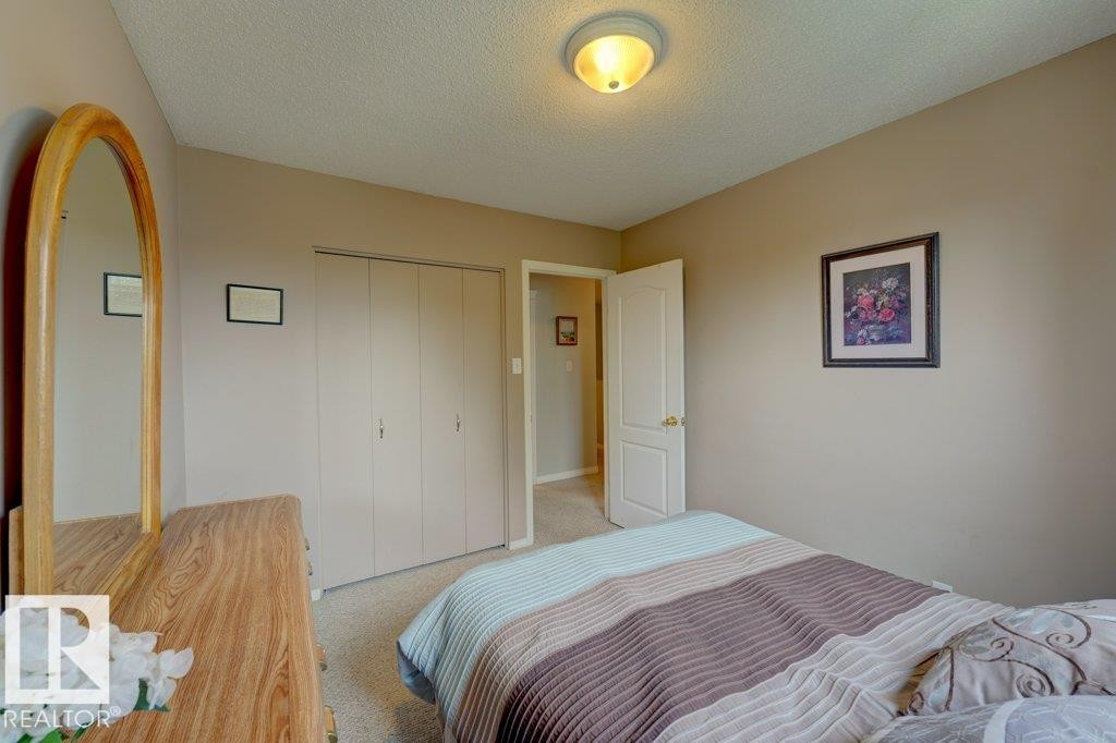 Spacious bedroom featuring warm wood-finish flooring, dual closets with white panel doors, and soft neutral wall tones - 307 Northgate Terrace Nw, Edmonton, AB - Indoor Photo Showing Bedroom