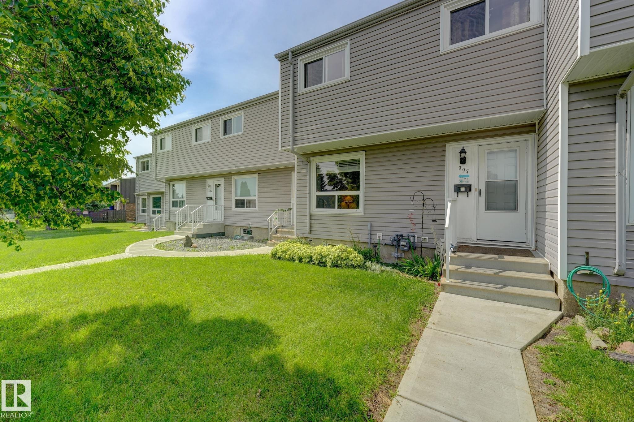 Two-story townhouse exterior with horizontal siding, concrete walkway, and a manicured lawn - 307 Northgate Terrace Nw, Edmonton, AB - Outdoor