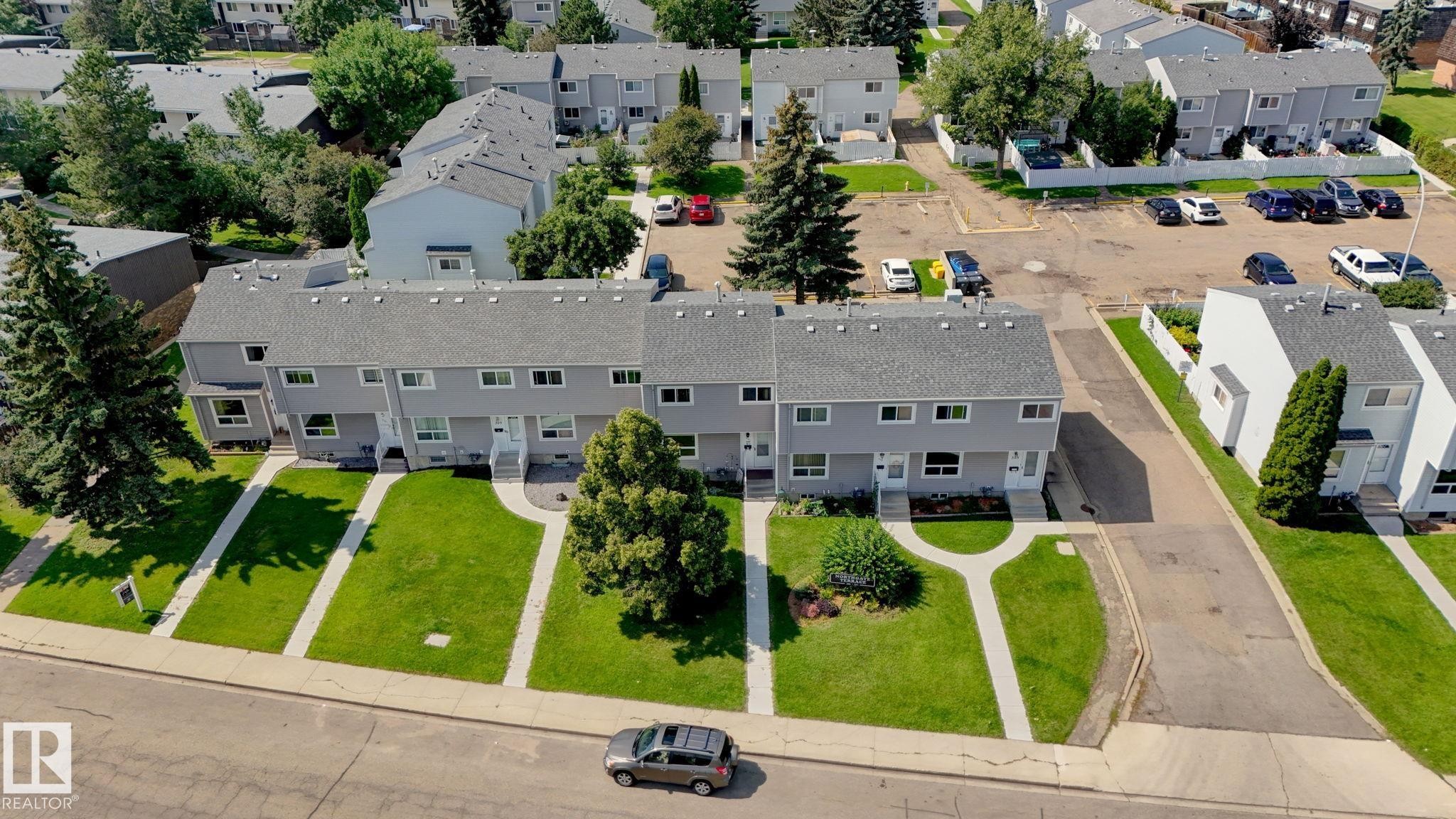 Modern townhome community featuring clean-lined architecture with multiple windows, manicured front lawns with mature landscaping, and generous green spaces throughout the development - 307 Northgate Terrace Nw, Edmonton, AB - Outdoor With View