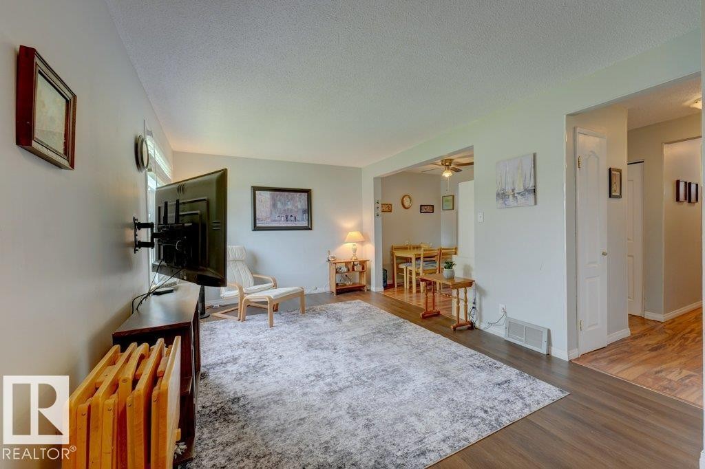 Spacious room with dark wood-finish flooring, light-colored walls, and a recessed dining area beyond - 307 Northgate Terrace Nw, Edmonton, AB - Indoor