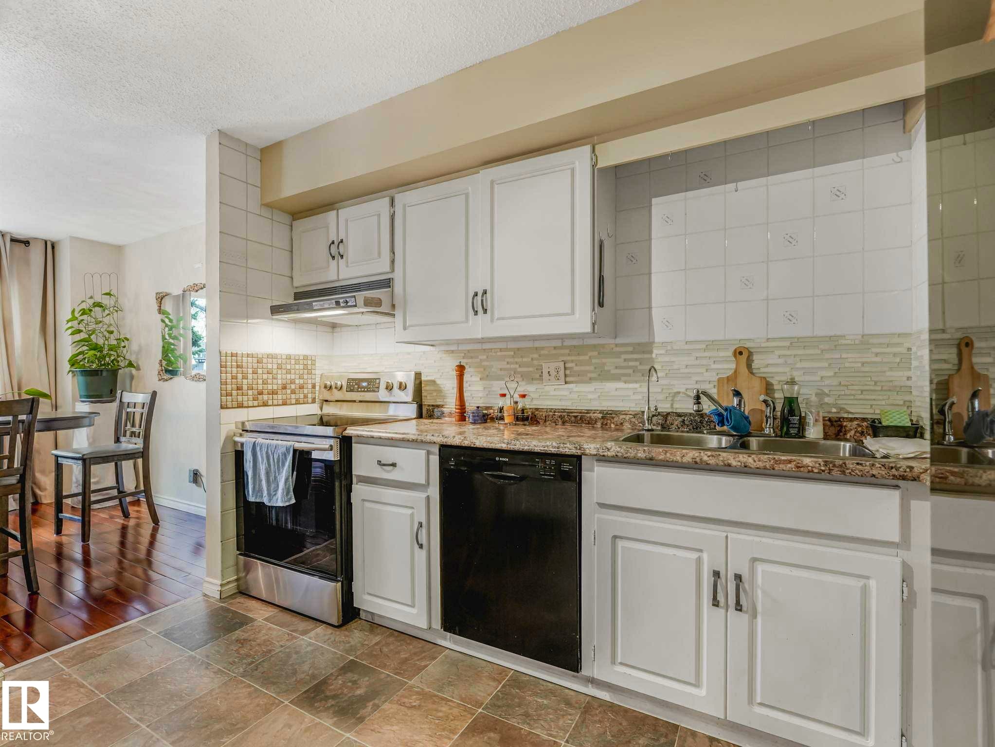 Kitchen featuring white cabinetry, tile flooring, and stone-look countertops - 13405 40 St Nw, Edmonton, AB - Indoor Photo Showing Kitchen With Double Sink With Upgraded Kitchen