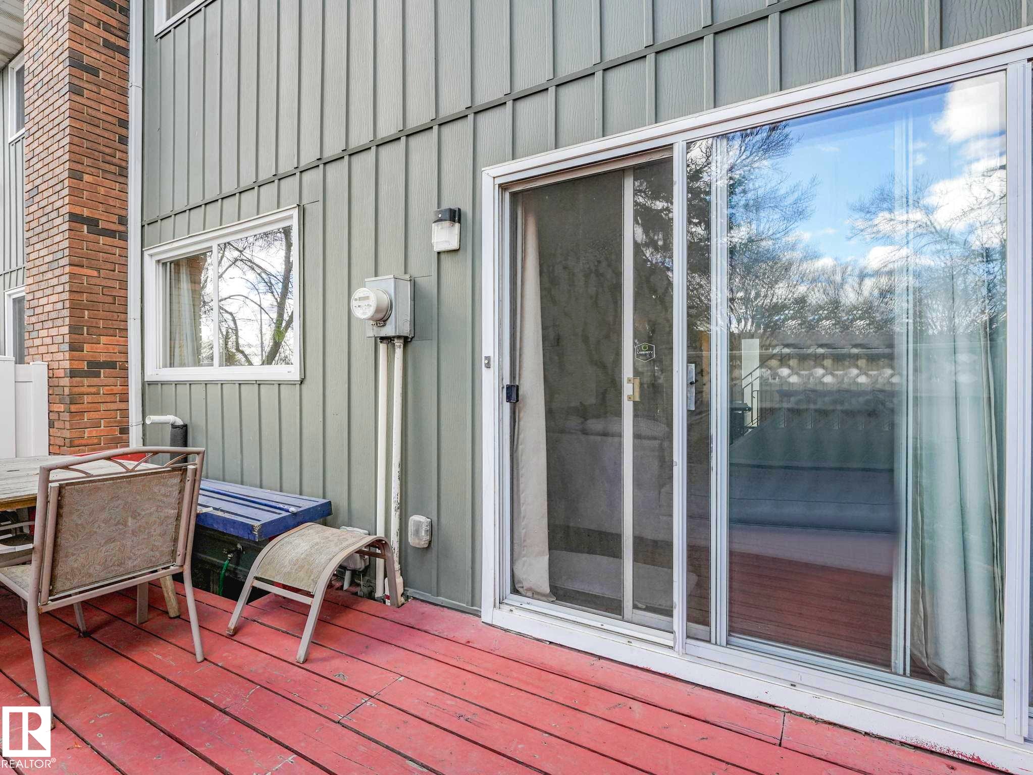 Expansive outdoor deck featuring red-painted wood planks and a white-framed sliding glass door - 13405 40 St Nw, Edmonton, AB - Outdoor With Exterior