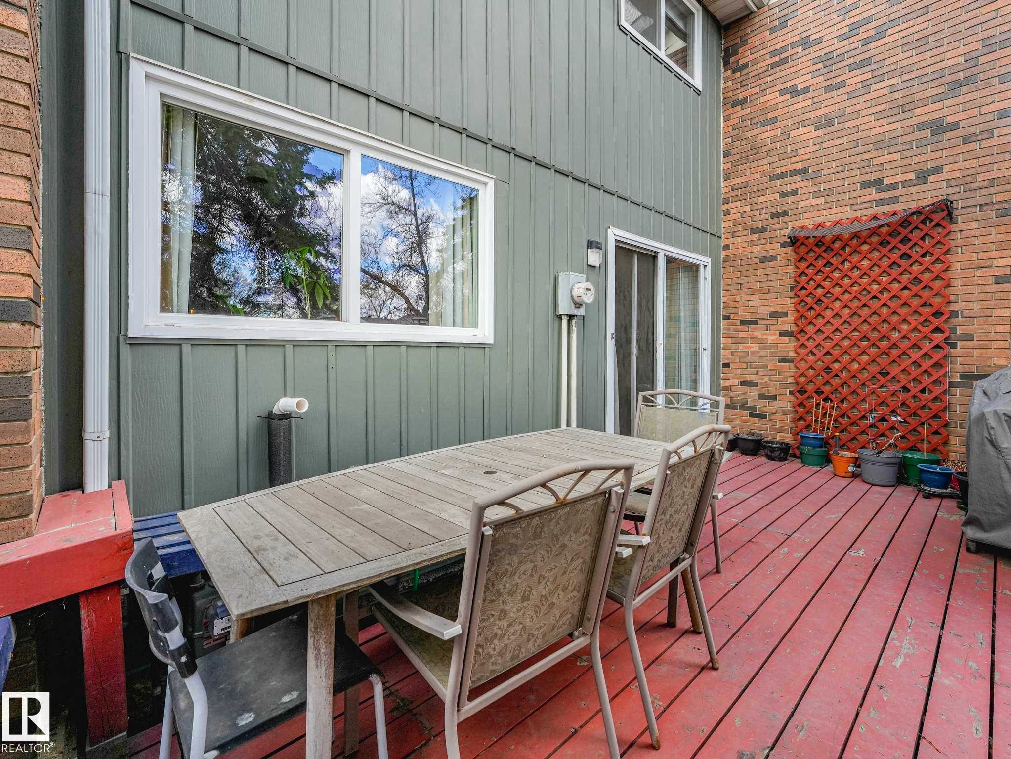 Red-stained wood deck featuring two distinct exterior claddings - 13405 40 St Nw, Edmonton, AB - Outdoor With Deck Patio Veranda With Exterior