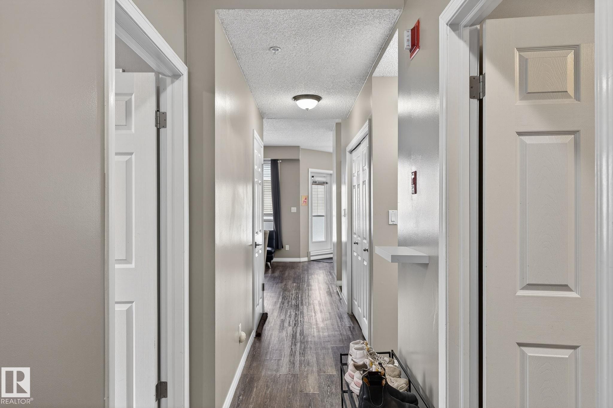 Hallway with wood-finish flooring, light neutral walls, and flush-mounted ceiling lighting - #103 8108 109 St Nw, Edmonton, AB - Indoor Photo Showing Other Room