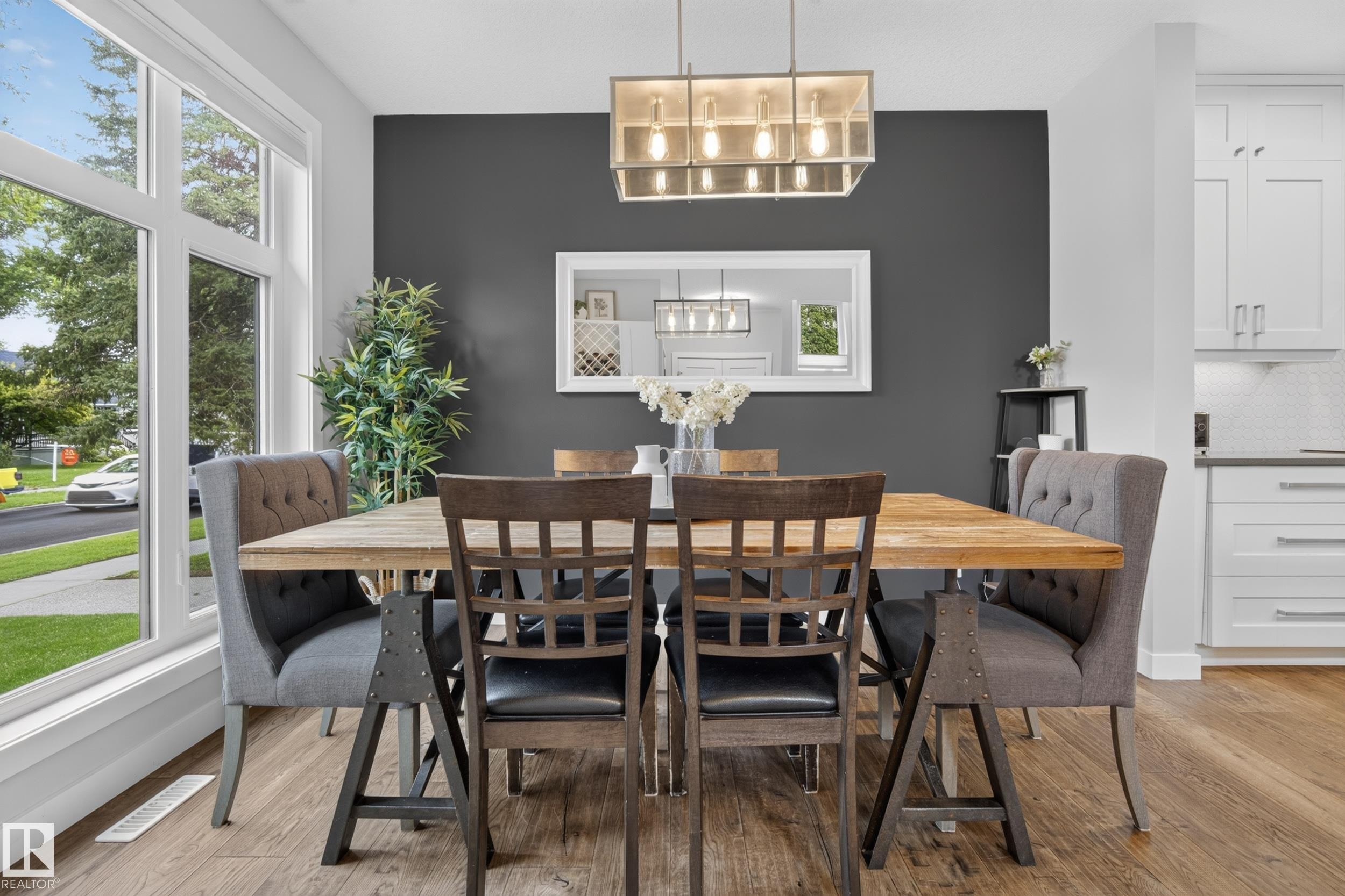 Expansive multi-pane window, wood-finish flooring, contemporary chandelier, white shaker cabinetry, and light-toned backsplash - 11018 122 Street Nw, Edmonton, AB - Indoor Photo Showing Dining Room