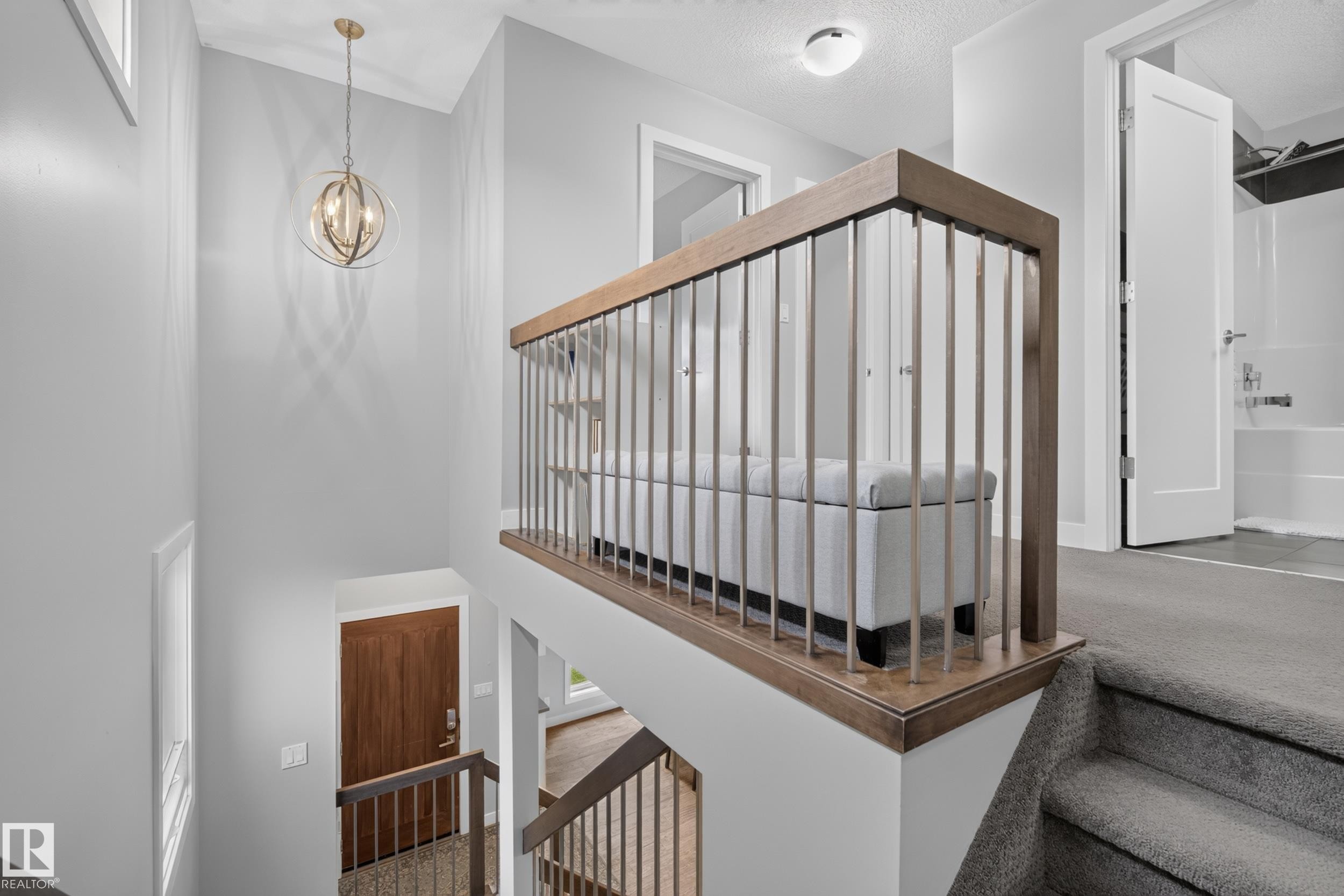 Wood-finish handrail with metal balusters, carpeted stairs, and a built-in light fixture - 11018 122 Street Nw, Edmonton, AB - Indoor Photo Showing Other Room