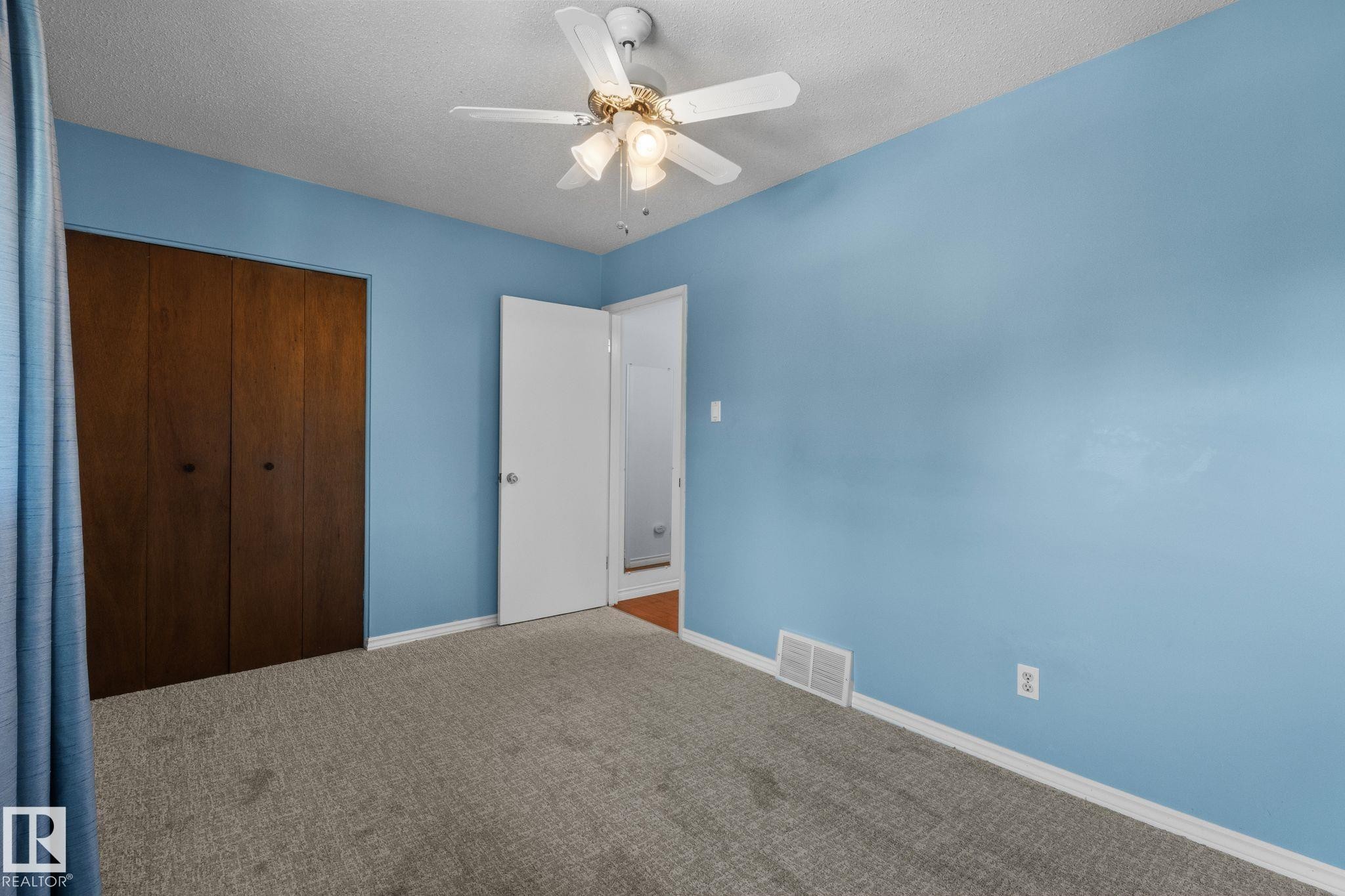 Wall-to-wall carpeting, wood-finish closet doors, and a ceiling fan with integrated lighting - 152 Woodstock Nw, Edmonton, AB - Indoor